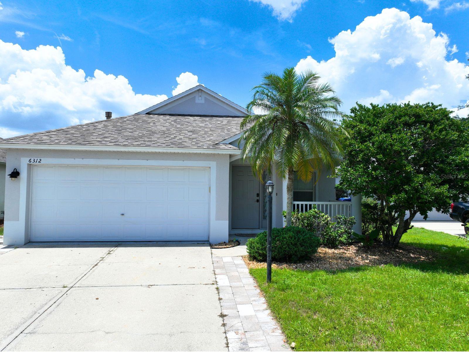 This is a fantastic opportunity to own a 4-bedroom, 2-bathroom home in Summerfield — located in the heart of Lakewood Ranch with plenty of upside potential. Nestled on a private cul-de-sac street lined with mature oak trees and well maintained grounds, this home offers charm and privacy.
The driveway features accent pavers and leads to a shaded front porch with ample seating space. Inside, you’ll find a single-slope vaulted ceiling and a main living area filled with natural light. The floorplan includes a spacious dining room, kitchen, and living room. The kitchen offers generous countertop space and ample cabinet storage, while the living room opens to the covered patio through large sliding glass doors. This practical layout places bedrooms 2, 3, and 4 off the main living and dining areas, with a private primary suite tucked away at the back of the home. The primary bedroom features its own set of sliding glass doors leading to the patio. Out back, you’ll enjoy a covered patio with brick pavers and a deep backyard—perfect for a pool, playground, or other outdoor activities. Summerfield is one of Lakewood Ranch’s most sought-after neighborhoods, offering excellent park amenities and a central location near top destinations like Waterside Place, Lakewood Ranch Main Street, and University Town Center.