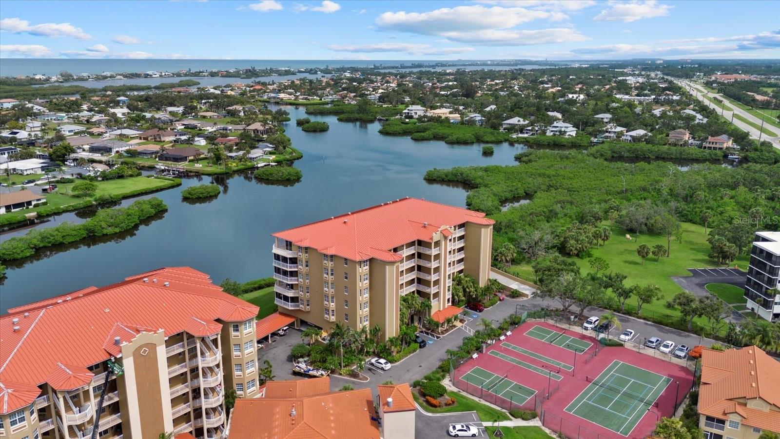 Perched on the top floor of Blackburn Harbor Residences, this 3-bedroom, 3-bath end unit is just under 2500 square feet and offers stunning, unobstructed vistas of the intracoastal waterways and Gulf of Mexico. Located within a gated, amenity-rich community, this condo features an open floor plan with high ceilings, a spacious kitchen, and a living area that seamlessly blends indoor comfort with awe-inspiring scenery. Step out onto the large wrap-around balcony—your private front-row seat to Florida’s most spectacular sunsets. The oversized primary suite offers a luxurious escape with two walk-in closets, an additional large closet, and a spa-like bathroom with a soaking tub, walk-in shower, and private water closet. The 2nd and 3rd bedrooms are generously sized, each with its own en-suite bathroom—perfect for hosting guests or providing a private, comfortable space for family members or a home office. Additional highlights include a new standing seam metal roof, two assigned parking spaces in the covered garage, and deep-water boating access with no bridges to the intracoastal—a rare find for boaters. Enjoy resort-style amenities within this meticulously maintained, pet-friendly community: heated pool, tennis and pickleball courts, kayak launch, clubhouse with fitness center, marina with available boat slips, lush walking paths, and a peaceful gazebo overlooking the water. Ideally located across from Oscar Scherer State Park and just minutes to restaurants, shopping, and award-winning beaches—Venice Beach and Siesta Key. This is the ultimate Florida lifestyle—spacious, scenic, and perfectly connected to land and sea.
