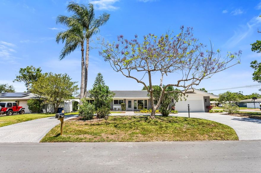Welcome to a beautifully remodeled mid-century home.  This 3 bedroom, 2.5 bath home sits on an oversized corner lot in the desirable Oak Acres sub-division.  Admire the new landscaping and beautiful stamped concrete circular driveway as you approach the home.  Inside, new flooring flows continuously throughout this light and bright open concept home.  The kitchen features a large island with plenty of seating and gorgeous quartz countertops.  All new appliances include the stove, dishwasher, microwave, garbage disposal, washer and dryer.   The new upgraded soft-close wood cabinetry provides for lots of storage.  The primary suite features a beautiful ensuite bath with large porcelain tiles and all new fixtures.  Sliding doors from the living room lead to the lanai which opens out to a large screened patio, complete with large specimen plants, perfect for relaxing or entertaining.  Rest easy with hurricane rated windows and doors throughout the house and a new hurricane rated garage door and opener.  Brand new tile roof and gutters, new paint inside and out as well as new R38 blown-in insulation.  Not in flood zone, non-evacuation zone, and no HOA. Centrally located, close to beaches and shopping.