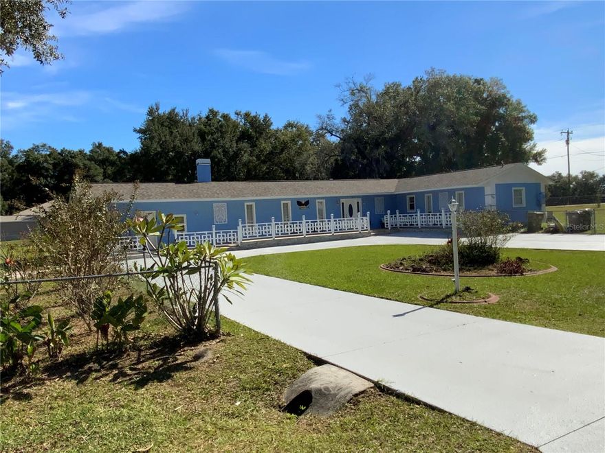 This remarkable property sits on a totally fenced 1.05 acres and impresses from the moment you arrive, greeted by a beautiful oversize circular driveway and exceptional attention to detail throughout. The front porch spans the entire front of the home. Stepping through the front door, you’ll find a spacious great room featuring an expansive living and dining area. Elegant ceramic wood-look tile flooring guides you to a cozy, full wall-to-wall brick fireplace that anchors the space with warmth and charm. The kitchen is a true showpiece, offering custom wood cabinetry, stylish accents, Top of the line appliances, custom countertops, and a comfortable dinette. The kitchen and dining area overlook the living room through a thoughtfully designed breakfast bar—perfect for entertaining. A built-in workspace with shelving adds convenience for those who work or study from home.  A large laundry room, which also doubles as a home gym, provides exceptional functionality. The romantic primary suite features custom wall accents, and a beautifully refinished bathroom complete with a glass-enclosed shower and separate vanity, along with a generous walk-in closet. A second primary suite includes its own private bathroom, while a third guest bedroom sits just off the dual French doors that open to the inviting patio and swimming pool.  Adding to its appeal, the property includes a huge versatile warehouse suitable for a variety of business or personal uses, a functional large storage shed, and plenty of space for a car or boat parking. The forth bedroom suite features an outside entrance, a living room and kitchen. It offers flexible options-ideal as separate living quarters, an in-law suite, or an income-producing rental unit.  The home is further enhanced by a new roof and new A/C system, providing peace of mind and modern comfort. A rare find with unmatched features-this home truly has it all.