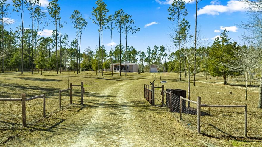 Your Slice of Paradise awaits on this 5-Acre Countryside Retreat! Located in a horse-friendly community surrounded by natural beauty, this property features a 3 Bed/2 Bath 2017 Double Wide by Palm Harbor, a new swimming pool, and tons of upgrades. NO HOA, NO Flood Zone! Central to Dunnellon and Ocala, a short drive from Goethe State Forest, Black Prong, and World Equestrian Center. An electric gate, scenic pine trees, and a screened-in front porch welcome guests into this charming homestead. Step into an open-concept layout accented with crown molding and abundant natural light, creating an elegant, warm, and inviting atmosphere. A spacious living room opens to a bright modern well appointed kitchen with a custom walk-in pantry, ample cabinetry, and center island with a raised bar. The master suite features a walk-in closet and a remodeled luxury en-suite boasting a captivating glass enclosed tile shower providing a peaceful retreat. Laundry/utility room with access from kitchen and rear exit door. The poolside provides a cozy outdoor escape and breathtaking views ideal for relaxing or entertaining guests. The metal carport-shed combo is perfect for all your tools and toys. Featuring a central, enclosed storage area with electrical hookup and a 12’ bay roll-up door flanked by two separate open-sided covered parking spaces with plenty of room for your autos, RVs, boats, campers, and travel trailers. The home is equipped with a newly added whole-house water filtration system. The central HVAC heat pump package unit is only six months old and includes a 10-year all-parts warranty with first-year labor coverage. The grounds are enhanced with self-sustaining, easy-care landscaping via an automated irrigation system serving the entire property. Your dream mini farm awaits away from it all but close to everything.