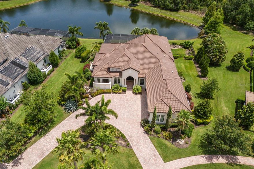 Situated privately on almost a half acre with stellar lake and preserve views in Lakewood Ranch, this meticulously designed and expanded Talia residence in the sought-after Eaglescliffe enclave in Country Club East showcases generously proportioned indoor-outdoor spaces, exceptional craftsmanship, IMPACT windows/doors/sliders, AND even boasts an oversized garage with car lift. 

Built by John Cannon Homes in 2018 offering 3,434 square feet of expansive one-story open living on a premier Lakewood Ranch lot with circular front drive, and an expanded lanai with a panoramic clear view screen, abundant open and under cover spaces, full summer kitchen, gas firepit, PebbleTec heated saltwater pool and large spa. 

Seamlessly connecting this resort-styled lanai to the oversized great room and dining area are disappearing 10’ impact glass doors that reveal a large open living concept with voluminous tray ceilings and wood beam detailing. Meanwhile chefs will delight in the beautifully appointed gourmand’s kitchen with SubZero, Wolf and Bosch appliances, sprawling stone counters, custom cabinetry with dovetail soft-close drawers, pull-out storage upgrades, reverse osmosis and a hidden walk-in pantry. 

Behind double French doors off the great room, lanai, and full pool bath is a voluminous bonus room with disappearing impact glass walls that open to reveal the serene outdoors. Additionally the residence offers an office with double-entry doors, built-in shelving and bench, shutters and wood flooring. 

Relax and unwind in the elegant owner’s retreat positioned on its own private wing, offering two oversized walk-in customized closets, and a luxuriously appointed spa-like bath with dual sink vanity, and both indoor and outdoor showers. Meanwhile, overnight visitors will be right at home in two generously sized guest suites both with private ensuite full baths. 

Other highlights of this 5,063 total square foot three bedroom and four full bath residence includes all impact windows and doors, a wine bar with two temperature-controlled refrigerators, built-in mud room storage and cabinetry, laundry room with cabinetry, sink, and closet, 8’ solid core interior doors, fenced back yard, tankless water heater, and rarely-available four car garage option with the addition of a car lift in this oversized 3-car garage with air-conditioned wall unit. 

Country Club East provides its residents with the privacy of gated-community living, three community pools, fitness center and easy accessibility to world-class shopping, dining, medical facilities & I-75, for an unparalleled lifestyle defined by relaxation & recreation. Residents also have the non-mandatory option to become members of the Lakewood Ranch Golf and Country Club, which offers four  championship golf courses, two clubhouses, tennis, pickleball, fitness center, heated pools, full social calendar and so much more.