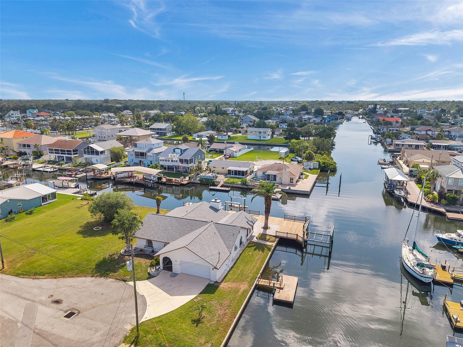 One or more photo(s) has been virtually staged. Welcome to your dream home in the sought-after coastal community of Hudson Beach Estates. Situated at the end of a quiet cul-de-sac on an oversized 0.27-acre lot, this waterfront stunner boasts 270-degree panoramic water views and over 200 feet of waterfront—a rare gem perfect for boaters and sunset lovers alike. This home features two floating docks, 2 boat lifts (one 16K and one 10K), and an expansive wraparound deck for entertaining, lounging, and taking in the views. Minutes to the open Gulf, only 5 canals away, this is a boater’s paradise. Step inside this newly remodeled home to an open-concept layout that seamlessly blends indoor and outdoor living. The kitchen offers beautiful quartz countertops, stainless steel appliances and white cabinets for that classic coastal feel. The spacious primary bedroom has a private ensuite, with walk-in shower, and two large closets. There are two additional bedrooms and a bathroom in a split-floor plan design offering privacy and comfort. The family room boasts a wood burning fireplace to snuggle up while enjoying the water views. There is a covered screen porch off the family room and a bonus room off the primary suite, ideal as a home office, guest lounge or game room. New roof installed in 2022. Bring all your toys! This waterfront community has sailboat deep water and is RV and golf cart friendly. There is a public beach just a short ride on your golf cart with waterfront restaurants and marinas. A 45-minute ride to Tampa International Airport. Close to New Port Richey’s historic downtown, rich with dining, culture and family-friendly activities. Come enjoy the Florida Waterfront lifestyle in this beautiful move in ready home. Schedule your private showing today! House is also listed fir sale, please see MLS # W7876520