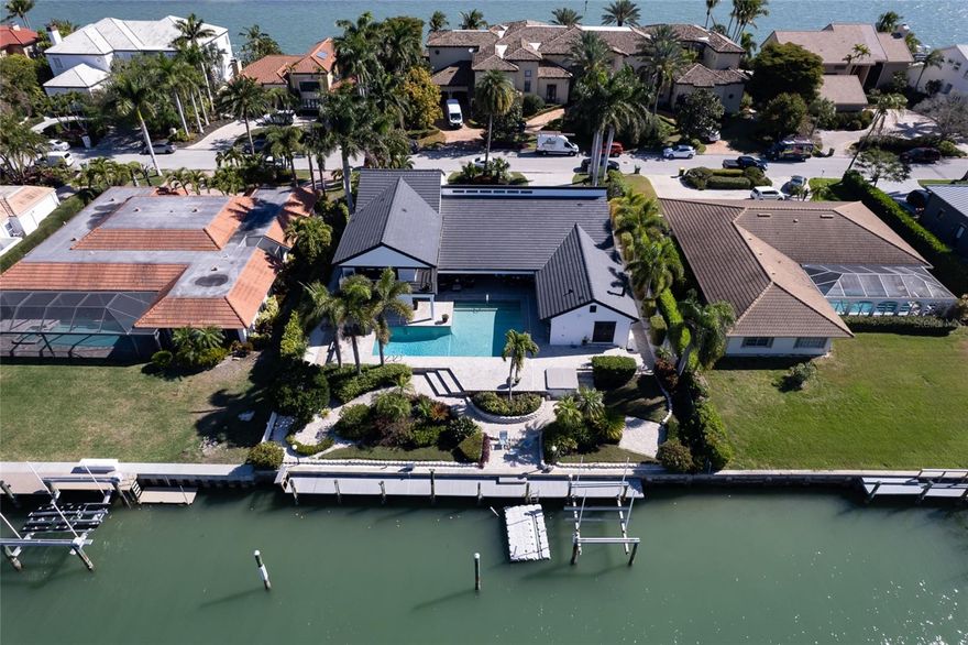 Imagine waterfront living with assurance of safety. This stunning property is perched at 12 feet above sea level, providing a serene waterfront lifestyle without risks associated with flooding. Remarkably, it has never flooded, even during the recent severe hurricanes that have impacted Florida. This property is the epitome of waterfront luxury in the highly sought-after Bird Key community. Prepare to be captivated by the sheer grandeur of this remarkable property, complete with an expansive, 100-foot-long deep-water dock. It is Meticulously designed to accommodate multiple vessels. Experience the ultimate convenience and peace of mind with its powerful boat lift, which can handle up to a 32-foot boat and lift up to 16000 pounds. The dock also includes a Kayak launch space. This state-of-the-art facility is designed to surpass all expectations. This deep-water dock is close to the bay and provides direct access to endless water adventures. It's all just a stone's throw away from your luxurious Bird Key abode. This exquisite luxury home offers a lifestyle of unparalleled elegance and sophistication. Boasting four spacious bedrooms, each accompanied by its full bathroom, ensuring privacy and convenience for every resident, a den, four full baths, and two half baths, this custom-crafted residence is a masterpiece of fine craftsmanship. As you step inside, you are greeted by a custom kitchen designed by Fine Craft, boasting a seamless design with no edges or handles, creating a sleek and modern aesthetic that is as functional as it is beautiful. The gourmet kitchen is equipped with top-of-the-line Thermador appliances. The kitchen is a chef's dream, perfect for creating culinary masterpieces or hosting elegant dinner parties. This exquisite home has been thoughtfully remodeled with a new roof and high-impact windows, ensuring a stylish living space and the highest level of safety and security. Step outside to your private oasis, where a huge saltwater pool with a spa awaits, surrounded by beautiful pavers that lead to a large pool area ideal for entertaining guests. Other features include Smart home controls, California closets with cedar in the master suite, granite and stone counters throughout the house also, a bar area with a wine cooler, four air conditioners, all under four years old, new duct work, beautifully paved circular driveway, two reasonably new water heaters, surround sound and speakers throughout, steam room, fireplace, special lighting throughout the house and outdoors, renewed stucco and freshly painted both inside and out.  This home offers luxury and convenience, with easy access to pristine beaches, upscale shopping, and fine dining establishments.  Whether you are relaxing in the elegant living spaces, unwinding in the luxurious bedrooms, or entertaining guests in the expansive outdoor areas, this home is designed to cater to your every need and desire. Contact us today to schedule a private tour and make this extraordinary residence your own. Live the life you deserve in this exquisite masterpiece.