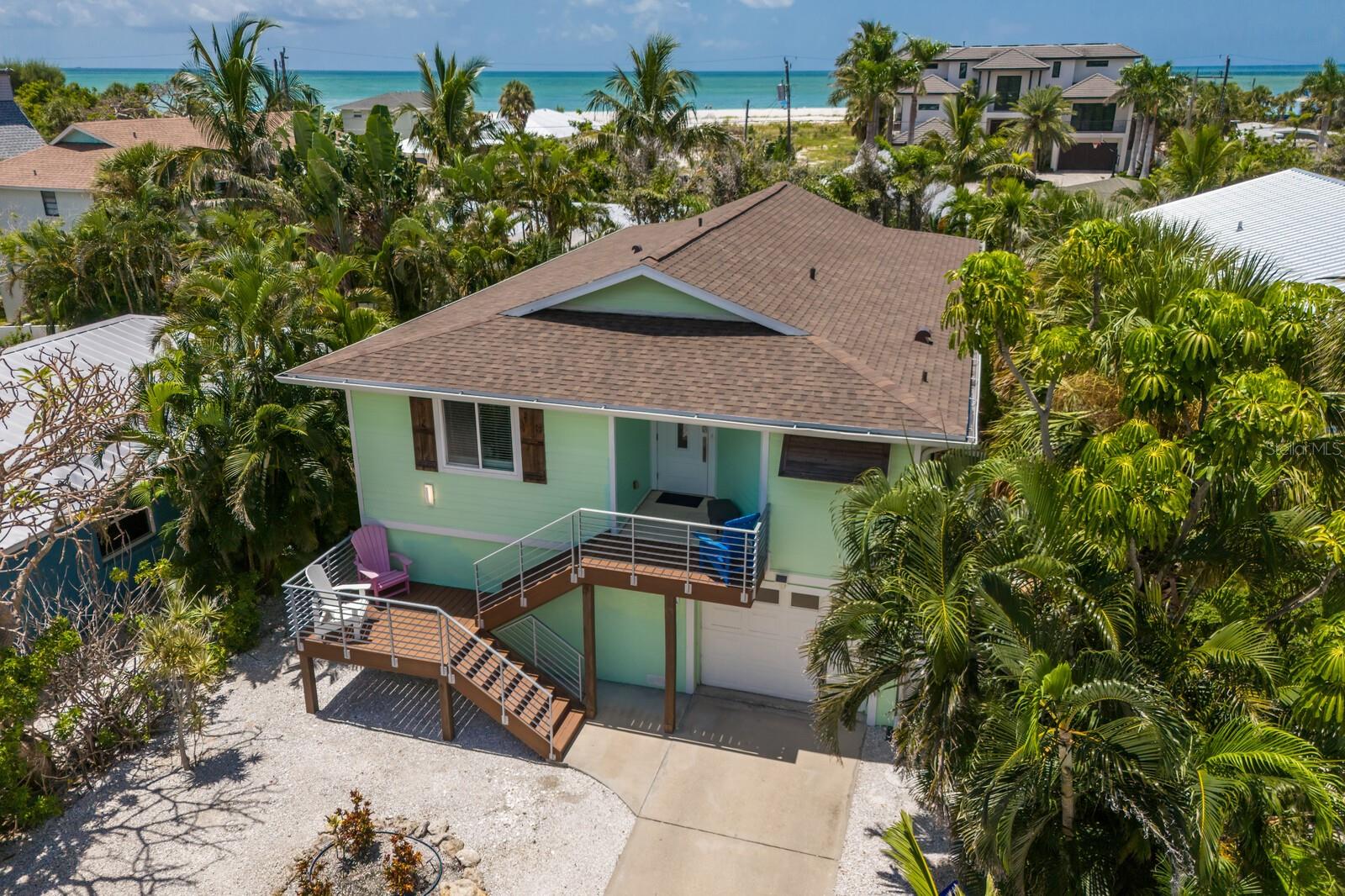 Welcome to Limelight — a beautifully appointed and fully furnished 3-bedroom, 2-bath coastal retreat ideally located on the coveted north end of Anna Maria Island, just steps from direct beach access. Light-filled interiors and swaying palms greet you upon entry, setting the tone for relaxed island living. Vaulted white wood-plank ceilings, custom millwork, wainscoting, and rich wood flooring create a warm and refined ambiance throughout the open living and dining spaces.
The kitchen, perfectly integrated with the main living area, features stainless steel appliances, granite countertops, a custom tile backsplash, breakfast bar, and a reverse osmosis drinking water system. The spacious primary suite includes a walk-in closet and en-suite bath with a walk-in shower. All bedrooms are finished with crown molding, custom wood trim, and wood floors, adding a touch of timeless character.
Step outside to the covered patio — the perfect spot to sip your morning coffee or toast the sunset. On the ground level, a stunning open-air living area offers relaxed lounging, alfresco dining, and even space to design your dream poolside bar — all enhanced by electric roll-down screens and hurricane shutters. The heated freeform pool is surrounded by lush tropical landscaping, offering complete privacy, along with a hot/cold outdoor shower.
Additional highlights include: a 2-car tandem garage with impact door, interior laundry with storage, impact-rated doors and windows, app-controlled tankless hot water heater and HVAC with AirKnight air purification, water softener and chlorine removal system, 2020 exterior stair and railing upgrades, 2024 new Tv in cabana area, 2024 new roof and an efficient drainage system.
Whether you’re looking for a full-time residence, second home, or investment opportunity, this island gem is move-in ready with nightly rentals permitted. Experience the best of Anna Maria living — laid-back luxury just moments from the Gulf.