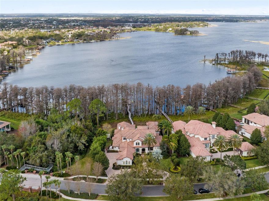 A home designed for entertaining and intimate gatherings focused on comfort, convenience, and functionality. Welcome to the guarded gated community of Reserve at Lake Butler Sound on the Butler Chain of Lakes. Extensive renovations in 2021 resulted in a beautiful and functional living space offering 6 bedrooms, 7.5 baths, an infinity edge pool, & cabana house with a full bath & requirements to create the recreation space or a separate bedroom suite. Rustic Spanish Mediterranean mahogany front doors open to 24' ceilings in the foyer with an exceptional pool & lake view. The living room boasts identical ceilings & views, with a cozy fireplace, perfect for relaxing with loved ones. Gorgeous 36" marble flooring spans from the foyer & formal areas into the kitchen, family room, and down the glass corridor. The bonus & game rooms, lofts, executive office, & all bedrooms offer new wood flooring. The formal dining area & spectacular new lighting are the ideal accompaniment for the redesigned fashionable chef's kitchen. New marble counters, a redesigned farmhouse island, stylish cabinetry, & top-of-the-line Viking & Sub-Zero appliances view the family room & dinette with restored beams. Large windows provide abundant natural light highlighting 12ft ceilings, a fireplace, and the perfect space for a Grand Steinway. Behind the kitchen is the brand-new modern-contemporary-designed frameless glass wine cellar showcasing your collection. Nearby is the bonus room, two bedrooms with ensuites, and a laundry area with a new second dishwasher, apart from the outdoor side-screened room with a fireplace. The first-floor owner's suite features a gorgeous view, an enormous spa-inspired private bath with a soaking tub & oversized shower, and a two-story closet with a center island, comfortable lighting, and ample space. An adjacent custom-built executive office with fine hardwood built-ins provides the perfect working environment. The second floor has a dedicated theater room with great sound, a massive projection system, and remote blackout blinds. The redesigned game room features a new bar, appliances, built-ins, and access to a grand veranda with a view of the resurfaced pool, patios, cabana, and the chain of lakes. You will also find two more bedrooms with full baths—one with plantation shutters and the other with remote blinds & access to the veranda. Between the floors is a unique kid's area with a loft. It's the perfect spot for play and creating new memories. Open the eight side-by-side French doors to the covered patio & BBQ kitchen with two wine refrigerators, ice maker, and a wet bar. Expand your entertaining outdoors, creating perfect summer barbecues, special occasions, and significant holiday events. The cabana house is ideal for guests or your private getaway, featuring new wood flooring, gas fireplace, & a remodeled full bath. Walk down the 200ft eco-friendly pathway leading to a 26x27 boat dock made of composite wood. The boat dock has a power lift and sensational views. Additional features include a basketball court, multiple fireplaces, a 4-bay side entry garage, 2 New HVACs, a New water heater, New dishwashers, wood ceilings, plantation shutters, remote blinds, & a Brand New Generac 60W natural gas generator providing power to the entire home power when needed. Historic downtown Windermere, Dr. Phillips, and the 408/429/Turnpike grant access to New hospitals, Disney World, OIA, and Central Florida.