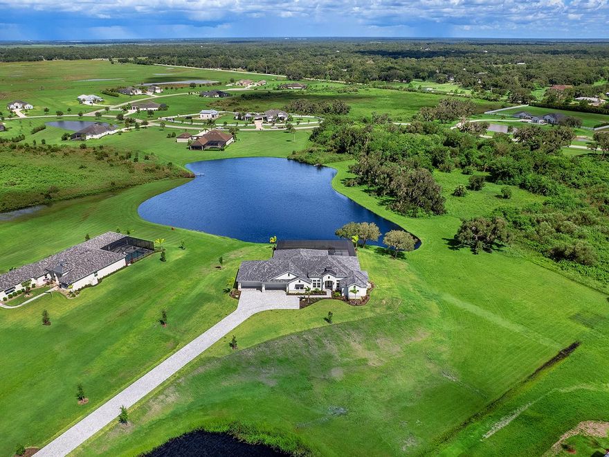 PRICE IMPROVEMENT - Loaded with over $800,000 in upgrades and designer options, this newly constructed estate at 3582 Recurve Circle sets a new standard for luxury living in Hampton Lakes. Set on a private 12-acre lot within a secure gated community, this stunning residence combines modern sophistication, exceptional craftsmanship, and serene lake views—all without the need for flood insurance.
A grand paver driveway leads to an oversized six-car garage, perfect for the car enthusiast or collector. As you enter through the light-filled foyer with soaring ceilings and tall windows, you’re immediately greeted by breathtaking views and an atmosphere of elegance and calm.

The expansive great room is the centerpiece of the home, featuring a stone-accented electric fireplace, custom wet bar, and walls of sliding glass doors that open to panoramic lake vistas. The outdoor living area is designed for entertaining, complete with a panoramic screen, self-cleaning saltwater heated pool and spa, and spacious covered lanai for dining or relaxing in total privacy. The gourmet kitchen is a true showpiece, boasting thick Cambria quartz countertops, induction cooktop, under-counter microwave, warming drawer, and adjoining butler’s pantry/wet bar with seating and a beverage cooler—perfect for both everyday living and hosting. The primary suite is a luxurious retreat with a spa-inspired bath featuring a jetted tub, large walk-in shower, and dual vanities. The impressive 15' x 18' custom closet includes built-ins and cabinetry, while a morning bar with beverage cooler adds an extra touch of comfort and convenience.

Each of the three guest en suites offers generous space, walk-in closets, and private baths for complete privacy. A den/office with French doors provides a quiet setting for work or reading. Modern elegance flows throughout the home, with large-format porcelain tile, impact-rated windows and doors, high-volume tray ceilings with accent lighting, and designer details at every turn.

Located just five miles from Waterside Place and Lakewood Ranch, with easy access to downtown Sarasota, this exceptional estate offers the perfect blend of refined country living and contemporary luxury. Experience sophisticated living at its finest at 3582 Recurve Circle in Hampton Lakes. GREAT VALUE AND PRICED BELOW REPRODUCTION.