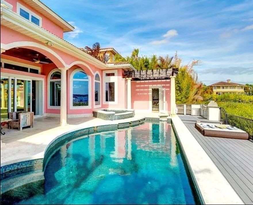 Exquisite tropical waterfront 4-bed, 3-bath, 2-car garage home featuring breathtaking open bay views and top-tier amenities for the most discerning buyer. The expansive open floor plan is designed to showcase stunning water vistas, with floor-to-ceiling glass walls seamlessly connecting indoor and outdoor living. Enjoy mesmerizing sunsets from your private dock with a lift, a chic outdoor entertaining area, and a brand-new heated saltwater pool with a spillover spa. Relax in the infrared sauna with hot/cold plunge pools or gather around the outdoor fireplace on the stunning porch, complete with an outdoor kitchen and panoramic water views. Luxurious finishes include elegant stonework and striking bamboo tray ceilings, creating the ultimate tropical retreat. The chef’s kitchen is equipped with Sub-Zero appliances, stone countertops, a wet bar with a wine cooler, and a butler’s pantry. The expansive second-level master suite features a private waterfront terrace, a designer custom closet, dual sinks, and a jetted spa bath. Located in a gated community with a two-car garage, this home offers the pinnacle of luxury waterfront living.