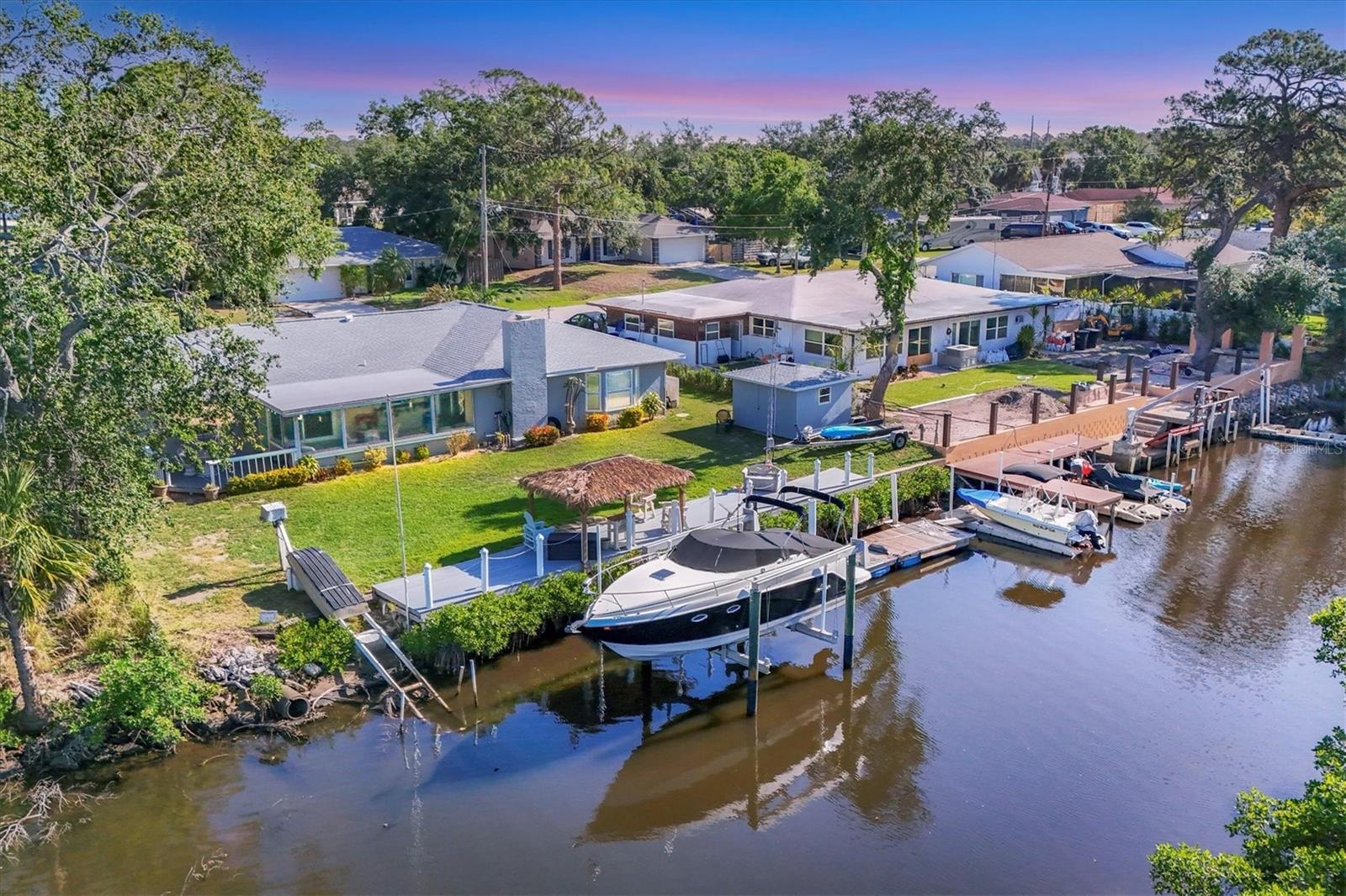 Boaters and water-lovers — this one’s for you! Welcome to your waterfront retreat on the beautiful Braden River! This charming 3-bedroom, 2-bath home is ideally positioned near the end of a quiet cul-de-sac with no HOA or CDD fees — offering privacy and freedom. A brand-new roof (2023) covers both the main house and the 10x10 detached workshop, perfect for hobbies, storage, or extra space. You’ll also enjoy peace of mind with clear polycarbonate hurricane shutters and the reassurance that this home has never experienced hurricane or flooding damage. Inside, the home boasts a desirable split-bedroom floor plan with updated wood-look tile flooring in the main living areas and plush carpeting in the bedrooms. The kitchen and bathrooms feature timeless classic oak cabinetry, blending functionality with charm. Step outside to your private backyard oasis where you can relax under your Tiki Hut with a brand-new thatched roof (2023) or head to your 59-foot TREX dock, complete with a private boat lift rated up to 13,000 lbs. Enjoy direct access to the Manatee River, with seamless navigation to the Intracoastal Waterway and Gulf of Mexico — making this home a true boater’s paradise. Located close to I-75, top shopping, dining, and everyday amenities, this property offers the ideal balance of peaceful waterfront living and modern convenience. Whether you’re searching for a full-time home or a weekend getaway, this unique property delivers the very best of Florida living. Bring your boat, your fishing poles, your tools — and your sense of adventure!