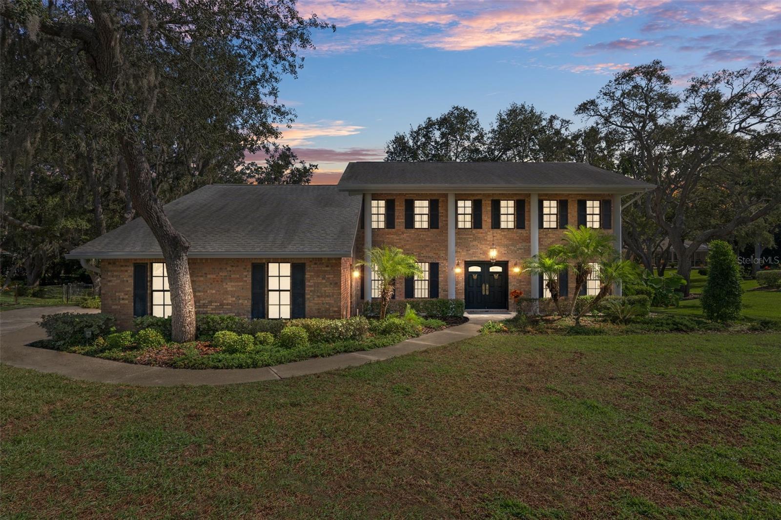 Welcome to 18706 Golden Hawk Court, a beautiful two-story brick-front home perfectly situated on a quiet cul-de-sac in the desirable and sought after community of Autumn Oaks. This elegant residence features four bedrooms, three full baths, and 2,378 square feet of living space, with a total of 3,225 square feet under roof. From the moment you arrive, the timeless colonial-style exterior with double-door entry, classic columns, and window shutters invite you in. Step inside to a spacious open foyer with hardwood floors and a traditional staircase leading to the upper level. This home offers formal living and dining rooms, along with a study/den with French door entry and built-in shelving. The separate family room is warm and inviting, centered around a beautiful brick wood-burning fireplace and double French doors that open to the screened lanai with wood decking. The downstairs guest bath includes a walk-in shower for added convenience. The kitchen is designed for both function and charm, featuring hardwood floors, an abundance of cabinetry, a center island with a prep sink, and a pantry, along with a cozy breakfast nook highlighted by a bay window and built-in window seat. The laundry room also features hardwood flooring, a sink set within a base cabinet, and ample storage space. Upstairs, the spacious primary suite offers a walk-in closet and a private sitting area that can serve as a nursery, home office, or quiet retreat. The en-suite bath includes dual sinks and a walk-in shower. The additional three bedrooms offer generous space, with one featuring built-in shelving and another showcasing hardwood floors. A full guest bath with a tiled tub and a hallway closet for added storage complete the upper level. Enjoy the outdoors in the large, screened lanai overlooking a beautifully landscaped half-acre lot with a chain-link fence perfect for entertaining or relaxing. The side-facing three-car garage is ideal for the hobbyist or car enthusiast, offering plenty of cabinetry, shelving, and workspace for projects, tools, or automotive work. Recent updates include AC systems replaced in 2017 and 2021, a new water heater in 2025, a new irrigation pump, and gutters and downspouts. Additional features include a well for irrigation, a sprinkler system, and a central vacuum. Located in a non-flood zone with no CDD fees, this home is nestled in a community that offers sidewalks, underground utilities, streetlights, and exceptional amenities such as lighted tennis courts, basketball, bocce ball, pickleball, a playground, and a barbecue area. Autumn Oaks is conveniently close to schools, shopping, restaurants, medical facilities, and Florida’s beautiful beaches, with easy access to Tampa and Orlando. This classic home blends elegance, comfort, and a prime location, making it a truly rare find.