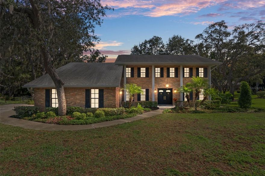 Welcome to 18706 Golden Hawk Court, a beautiful two-story brick-front home perfectly situated on a quiet cul-de-sac in the desirable and sought after community of Autumn Oaks. This elegant residence features four bedrooms, three full baths, and 2,378 square feet of living space, with a total of 3,225 square feet under roof. From the moment you arrive, the timeless colonial-style exterior with double-door entry, classic columns, and window shutters invite you in. Step inside to a spacious open foyer with hardwood floors and a traditional staircase leading to the upper level. This home offers formal living and dining rooms, along with a study/den with French door entry and built-in shelving. The separate family room is warm and inviting, centered around a beautiful brick wood-burning fireplace and double French doors that open to the screened lanai with wood decking. The downstairs guest bath includes a walk-in shower for added convenience. The kitchen is designed for both function and charm, featuring hardwood floors, an abundance of cabinetry, a center island with a prep sink, and a pantry, along with a cozy breakfast nook highlighted by a bay window and built-in window seat. The laundry room also features hardwood flooring, a sink set within a base cabinet, and ample storage space. Upstairs, the spacious primary suite offers a walk-in closet and a private sitting area that can serve as a nursery, home office, or quiet retreat. The en-suite bath includes dual sinks and a walk-in shower. The additional three bedrooms offer generous space, with one featuring built-in shelving and another showcasing hardwood floors. A full guest bath with a tiled tub and a hallway closet for added storage complete the upper level. Enjoy the outdoors in the large, screened lanai overlooking a beautifully landscaped half-acre lot with a chain-link fence perfect for entertaining or relaxing. The side-facing three-car garage is ideal for the hobbyist or car enthusiast, offering plenty of cabinetry, shelving, and workspace for projects, tools, or automotive work. Recent updates include AC systems replaced in 2017 and 2021, a new water heater in 2025, a new irrigation pump, and gutters and downspouts. Additional features include a well for irrigation, a sprinkler system, and a central vacuum. Located in a non-flood zone with no CDD fees, this home is nestled in a community that offers sidewalks, underground utilities, streetlights, and exceptional amenities such as lighted tennis courts, basketball, bocce ball, pickleball, a playground, and a barbecue area. Autumn Oaks is conveniently close to schools, shopping, restaurants, medical facilities, and Florida’s beautiful beaches, with easy access to Tampa and Orlando. This classic home blends elegance, comfort, and a prime location, making it a truly rare find.