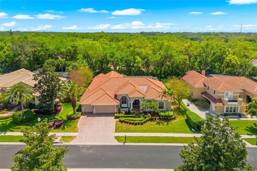 Welcome to 1560 Canopy Oaks Boulevard, an exceptional single-story Mediterranean-inspired estate crafted by acclaimed builder Marc Maconi, featuring architectural elegance, luxury finishes, and functional design. Located within the gated Manning Oaks community, this nearly one-third-acre property presents a rare opportunity to own a home where every detail has been thoughtfully curated for comfort and quality.

The north-facing façade showcases a tile roof, block construction, and maintained tropical landscaping. Mature greenery and manicured lawns frame the home’s Mediterranean silhouette, creating a welcoming arrival while maintaining privacy. Underground utilities keep the streetscape unobstructed, and the three-car attached garage provides space for vehicles and storage.

Step through the double entry doors into over 3,340 square feet of heated living space, where cathedral and vaulted ceilings, expansive windows, and an open floorplan create a light-filled environment. The interior combines seem less wood look luxury vinyl plank flooring throughout. Architectural millwork, including crown molding, archways, and trim, reinforces the home’s craftsmanship.

The kitchen is outfitted with solid wood cabinetry, a built-in convection oven, gas cooktop, stainless appliances, trash compactor, and wine refrigerator. A high bar is perfect for afternoon snacks or meals. A whole-house reverse osmosis system supports water quality throughout. The kitchen opens to the family room with a masonry gas fireplace, while formal living and dining spaces provide flexibility for everyday use or entertaining.

The main-floor primary suite features cathedral ceilings, dual walk-in closets, and access to the screened lanai and covered patio. The en-suite bath is designed for daily comfort. Four additional bedrooms provide flexible space for family, guests, or home offices, along with three full bathrooms.

Step outside to a screened lanai and covered patio overlooking a private in-ground pool. The .32-acre lot provides outdoor space while maintaining privacy.

Additional features include a whole-house water softener and reverse osmosis system. Located in Flood Zone X, the property provides added peace of mind and is connected to public water, sewer, electricity, and natural gas.

Situated within the Palm Harbor University High School zone, this home is zoned for well-regarded schools. Residents also benefit from the gated Manning Oaks homeowners association, which maintains community standards. Nearby access includes Gulf Coast beaches, parks, and local amenities.

The layout, finishes, and indoor-outdoor connection support both everyday living and entertaining. With its location, construction quality, and thoughtful design, 1560 Canopy Oaks Boulevard presents a well-rounded opportunity for buyers seeking space, privacy, and long-term value.