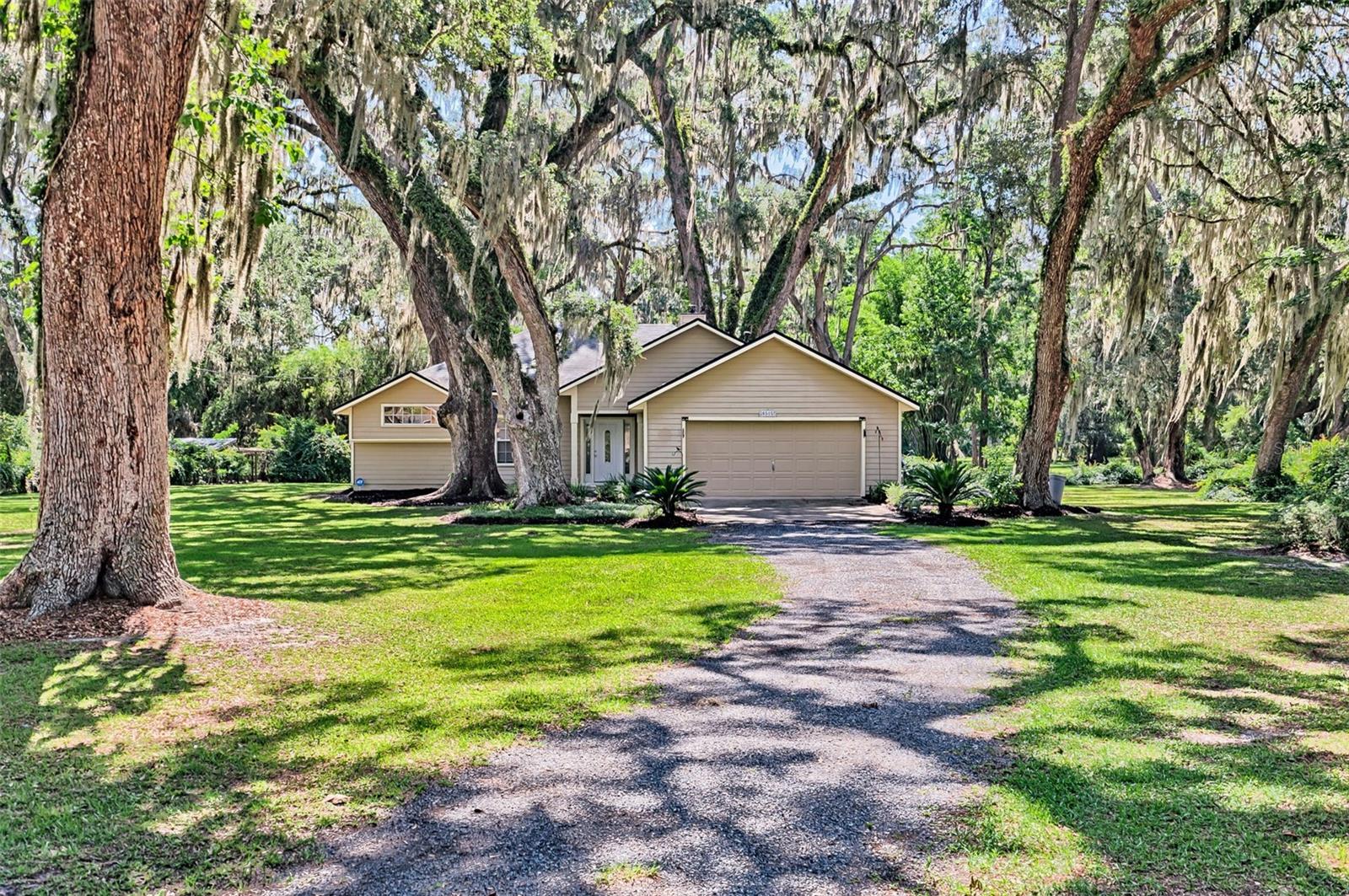 Discover serene country living just minutes from Gainesville in this beautifully renovated retreat, nestled on over an acre under majestic oak trees. This exceptional 3-bedroom, 2-bathroom split-plan home offers modern comfort and privacy—with the owner’s suite thoughtfully separated from the guest bedrooms by the gourmet kitchen, great room, and living areas for flawless flow and convenience.
Step inside to a newly updated gourmet kitchen featuring quartz countertops, tall shaker cabinets with soft-close drawers, stainless appliances, and a large island that opens to the great room—anchored by a cozy wood-burning fireplace. The generous owner’s suite boasts a fully renovated master bathroom, offering a serene private sanctuary. On the opposite side of the home, two spacious guest bedrooms flank the freshly renovated guest bathroom—ideal for hosting or creating a quiet workspace. This well-designed layout ensures both entertaining and rest happen seamlessly, without disruption.
Extra perks include luxury vinyl plank flooring throughout the main areas, fresh interior paint, refaced fireplace, new lighting fixtures, water filtration system, and a newer roof. Plus, you can save on your monthly energy bills thanks to Clay Electric Cooperative’s not-for-profit structure. With an easy-to-live-in layout, modern updates, and timeless country charm—plus long-term savings on utilities—this home is truly a must-see!