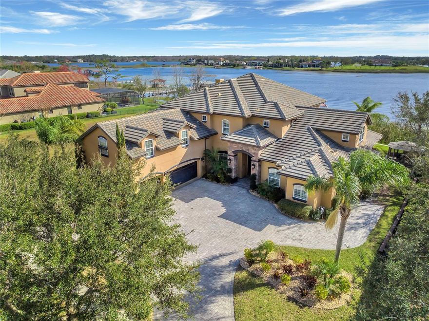 Extraordinary and luxurious LAKEFRONT on Lake Hancock custom-built estate with an attached private entrance to a guest/in-law suite that sits on over 1.60 acres with nightly panoramic views of world-class Disney Fireworks. The Mediterranean-style estate zoned in the top-rated school area includes 99 feet of water frontage with a rare opportunity to own an estate with a commercial-grade seawall front-facing North, allowing perfect views for watching both the Sunrises and Sunsets over Lake Hancock’s 475 acres. Upon entering the home, you are immediately captivated by gorgeous lakefront views and breathtaking touches including soaring tray ceilings, Anderson hand-scrapped hardwood flooring and generous entertaining spaces with formal dining and living areas, a gourmet kitchen, and an exquisite first-floor owner’s retreat with sitting area, separate shower, soaking jetted tub, travertine flooring, and double custom closets. The chef’s kitchen features a gas cooktop, island, farm-house sink, pot filler, side-by-side Thermador refrigerator, custom cabinetry, walk-in pantry, and granite counters that overlook the family room and eat-in areas with stunning views of the lake. The family room has an elegant stone fireplace with custom built-ins. One guest room is downstairs while the other 4 are upstairs, including a guest en-suite with a private balcony. The seventh guest room is located through a separate staircase entrance. Outdoor living at its finest with an Infinity pool, enclosed gazebo, kitchen tiki bar, MistAway misting system, and a large fenced yard allows for space to run and enjoy yard games. The 3-car garage has epoxy flooring and an oversized walk-in storage closet as well as upper shelving. The home is equipped with CAT5 wiring with RJ45 ethernet connections throughout the home and has a total of two laundry rooms, one upstairs and one downstairs for convenience. HOA fees include Cable and internet as well as resort-style amenities: 2 community pools, a large community park, 2 dog parks, play areas, 2 private boat ramps with docks, tennis and basketball courts, a main clubhouse with arcade, fitness & 2nd clubhouse both with fitness room & billiards, 10’ walking/biking path thru-out community. There are also fantastic community events planned by full-time community event planners & on-site community property mgr. Local residents enjoy the convenience of the nearby exercise trail, parks, shops, dining, brewery, a luxury Movie- Theater, and more at The Horizon’s West Hamlin Town Center; one of the fastest-growing communities in the US. Residents are actively walking, running, bicycling & driving golf carts to the Town Center while looking forward to the future plans of a dockable Tiki bar, Tiger Woods Pop Stroke, and more entertainment and restaurants. Find more here: https://hamlinfl.com/ **YES, YOU CAN BUILD A DOCK ** This is your opportunity to live the lake life!  Video: https://www.tourdrop.com/dtour/371124/Video-MLS