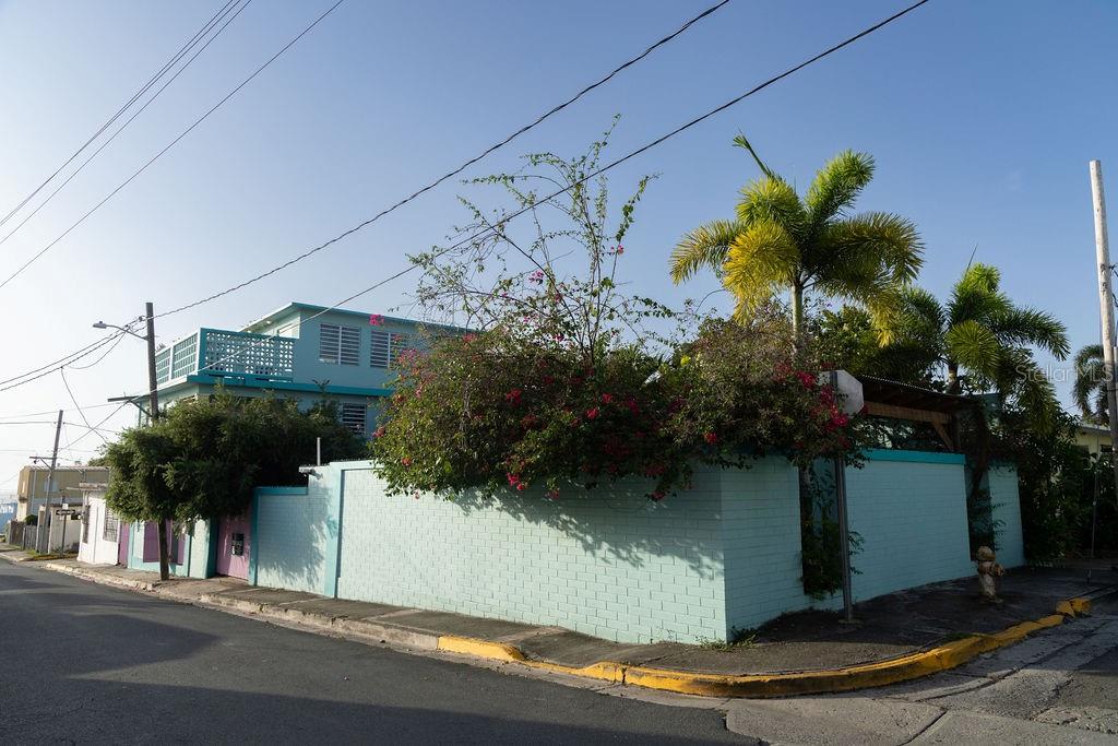 This urban three-story house is just a short walk from Playa de los Muertos (a.k.a. Sea Glass beach) and all the amenities of living in the Caribbean town of Isabel II. It’s traditional Spanish and colorful Creole architecture includes classic Puerto Rican breeze blocks and decorative rejas.
Upon entering the property, a fabulous outdoor courtyard and garden reminiscent of Spanish Cloisters greets you. The elegantly centered pool is lined with iridescent blue tiles and flanked by the two sculptural lion fountains that give the home it’s name, fill the house with the water’s relaxing sound.
The property is divided into three separate living quarters. The main level is perfect for entertaining and receiving guests. The common meeting grounds have an outdoor wet bar and poolside dining shaded under the bougainvillea, also great for spending the evenings playing cards or lounging with friends and family. The spectacular outdoor space connects with a spacious living room and oversized fully equipped kitchen with bar seating and dining space. At the rear is a full bath and a quiet air-conditioned guest bedroom with its own cozy and private outdoor green patio.
The upper level principal suite is the ideal place to retreat from the urban atmosphere into a quiet and intimate environment and enjoy views of the north-side ocean. The large open area has an ensuite bathroom and kitchenette, offering the quarters complete privacy. The fully air-conditioned space also boasts it’s own living room for lounging and a dining/remote workspace. The outdoor balcony is a perfect place to hang a hammock, read a book or take a siesta surrounded by ocean views and plants.
Below, the second level offers plenty of space for family and guests with two air-conditioned bedrooms with a shared full bathroom/laundry and living space. To the left a secondary bedroom has its own outdoor sitting area, while the righthand bedroom has it’s own workspace.
The courtyard has a carport gate to station one car while away from Vieques. The outdoor pump room has space for additional storage. With a 3,312 sqft lot, its convenient location and beachside charm, this house would be a great place to call home or investment property.