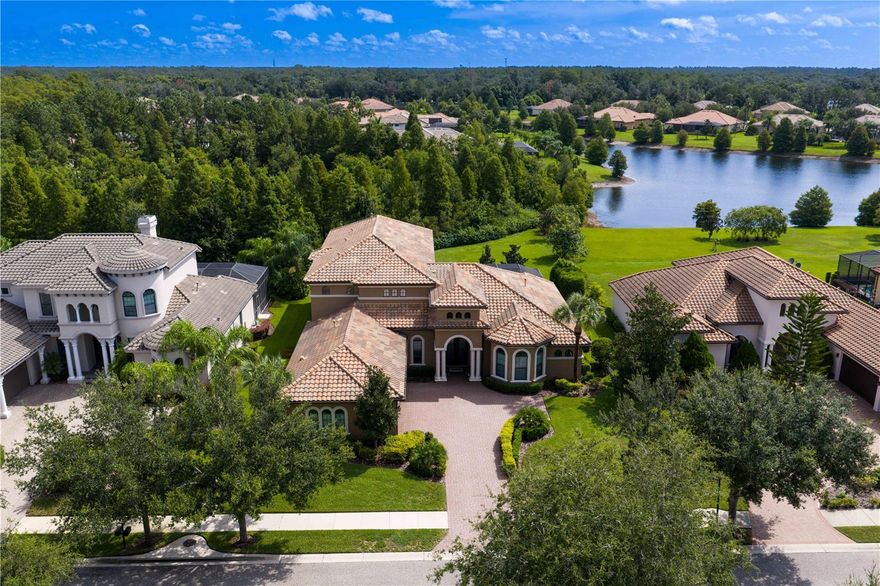 The charm of Ladera Estates - live expansively, privately, and beautifully.  Known for it’s blend of tranquility and convenience, Ladera Estates offers a unique, gated lakefront community on Lake Merrywater.    Welcome to 1213 Merry Water Drive with a timeless design, modern comfort, and breathtaking natural surroundings. Built in 2015 and situated on just under an acre with no rear neighbors, this custom-built residence offers 4882 sq ft of total living space.  Set on .98 of an acre, this estate is designed for both grand entertaining and everyday luxury. Key Features: • GREAT ROOM – Enter through double doors into the Great Room with 12-ft ceilings, surround sound, and views of the pool, conservation and pond. A comfortable family room with sliding glass doors for seamless living to the outdoor terrace. • DESIGNER KITCHEN – An oversized granite island anchors the space, complemented by a hidden walk-in pantry with a coffee bar and dining room built in storage. Open concept living with an oversized casual dining room - ideal for gatherings large or small. • PRIMARY SUITE & MAIN LEVEL ROOMS – The main-level primary suite includes dual custom walk-in closets, and spa-inspired bath with freestanding tub and oversized walk-in shower. Three additional bedrooms, as oversized study, and drop-zone with built-ins next to a large laundry room complete the thoughtful main floor. • UPSTAIRS LIVING – Two oversized suites upstairs, each with private baths and large closets—perfect for guests, teens, or multigenerational living. The upstairs entertainment zone includes a large bonus room, wet bar with fridge, and balcony overlooking the serene pond and backyard conservation views. A separate movie room with 1/2 bath complete this entertainment space • RESORT-STYLE LIVING Heated pool with sunshelf, covered and fully screened terrace, full summer kitchen, and access to a pool bath. Lush, mature landscaping and lots of extra green space are a perfect space for play or pets• ADDITIONAL HIGHLIGHTS – Features 8-foot doors on both levels, 3-car garage, custom-finished walk-in closets, pantry and additional storage closet, crown and tray ceilings throughout. • This estate is more than a home- it’s a retreat. Wake up to sunrise views, unwind in complete privacy, and enjoy the serenity of expansive natural surroundings that draw you to Ladera Estates.• Located in Lutz- one of the Tampa Bay area’s most sought-after communities for its natural beauty, larger homesites, and tranquil lifestyle- you’ll enjoy the peace of country-style living with the convenience of being just minutes from top-rated schools, hospitals, dining, shopping, major highways, and Tampa International Airport. It’s the perfect balance of space, serenity, and accessibility.