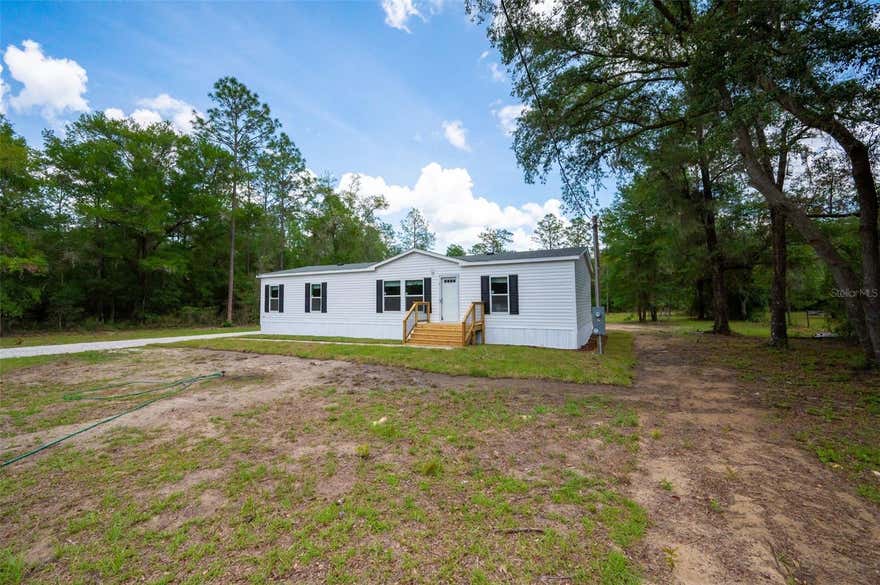 Welcome home to this brand-new 2026 Live Oak Sprinter manufactured home, offering modern comfort and peaceful country living on large wooded lot in beautiful Bronson, Florida. This spacious home offers approximately 1,500 square feet of living space, featuring 3 bedrooms and 2 full bathrooms with an open, functional layout perfect for everyday living. The kitchen is equipped with brand-new appliances, including a refrigerator with icemaker, new stove and range, and a new dishwasher. A washer and dryer, NEWER, are included for added convenience. Inside, you’ll find durable laminate vinyl plank flooring throughout, creating a clean, contemporary feel while being easy to maintain. The open living and dining areas flow seamlessly into the kitchen, providing plenty of space for entertaining or relaxing with family. The primary suite includes a private bath. Step outside to an 8’ x 16’ wooden deck, overlooking the backyard—an ideal space for morning coffee, grilling, or enjoying Florida evenings. The property features fresh sodding around the perimeter, creating a clean, finished outdoor appearance.