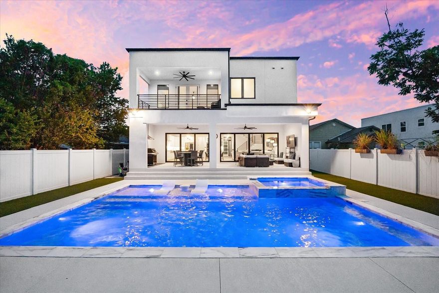 A home of rare presence and purpose, 2707 Ridgewood Avenue blends refined architecture with effortless livability in one of Tampa’s most established neighborhoods. Completed in 2023 by NEO, this five-bedroom, four-and-a-half-bathroom residence is defined by clean lines, intentional flow, and beautifully curated materials. From the moment you enter, natural light pours through oversized windows, setting the tone for airy, open-concept living. Wide-plank engineered hardwood floors guide you through soaring spaces that feel both expansive and grounded. The kitchen—centered around an oversized island—is outfitted with high-performance appliances including a gas cooktop, wine refrigerator, and tankless water heater, with custom cabinetry and stone surfaces throughout. The great room opens through sliding doors to a private outdoor retreat. A heated saltwater pool and spa are surrounded by covered lounge areas, a built-in grill, and Florida-friendly landscaping with irrigation, all enclosed by privacy fencing, turf lawn. It’s a seamless extension of the home—designed for entertaining, built for quiet moments. Upstairs, the primary suite offers spa-like comfort, complete with soaking tub, glass shower, dual vanities, and a custom walk-in closet. French doors open onto the balcony overlooking the city. Three additional bedrooms are generously sized, each offering en suite bathrooms with built-in closets. A full-size laundry room is conveniently located on the second floor. The fifth bedroom, located on the main level, is ideal for guests, den-office-study or multi-generational living. Additional features include a two-car attached garage, touchless entry, security lighting, water softener system, and energy-efficient climate control. Built on a stem wall foundation in Flood Zone X, the home qualifies for hurricane insurance deductions and offers long-term peace of mind. Ideally located just minutes from Tampa’s Riverwalk, Armature Works, and Downtown, this property offers sophistication, flexibility, and a lifestyle rooted in both design and location.