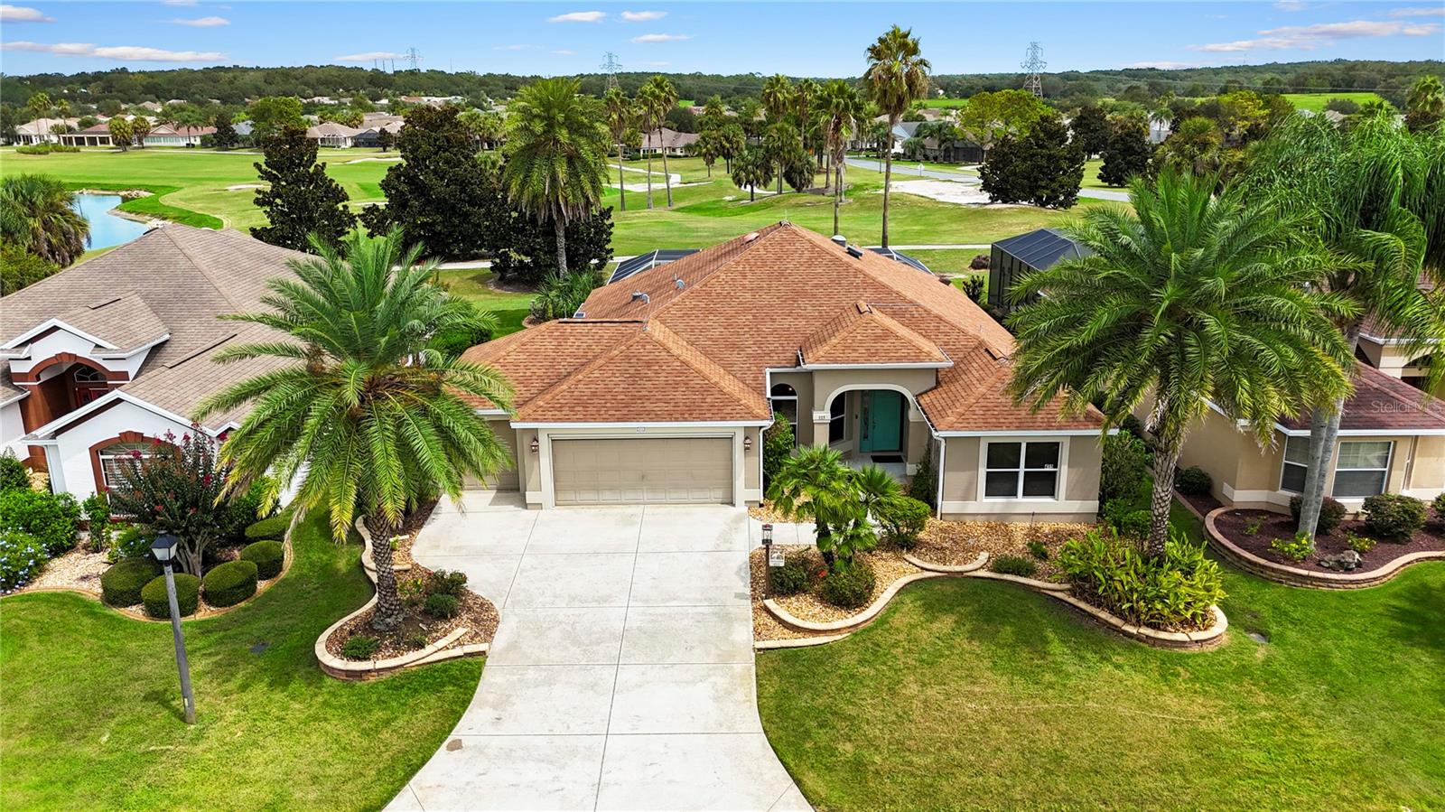 One or more photo(s) has been virtually staged. This beautifully appointed Gardenia floor plan boasts a 2-car plus golf cart garage and is perfectly situated on the Havana Championship Golf Course with stunning panoramic views. The exterior showcases an oversized 4-foot extended lanai with pocket sliders that open to a sparkling pool surrounded by cool deck flooring and warmed by a Hayward EasyTemp heat pump—the ultimate setting for entertaining or simply relaxing while enjoying the tranquil golf course scenery. The lush Florida landscaping further enhances the curb appeal with stacked stone borders, towering Sylvester palms, and rock-filled flower beds. Inside, the home features a split and open floor plan with volume ceilings, knockdown texture, and 5 ¼" baseboards. A solar tube in the living room brings in natural light, while tile laid on the diagonal flows through the main living and wet areas. The kitchen is a showpiece, offering staggered cabinetry with glass inserts, pull-out shelving in the pantry, under-cabinet lighting, granite countertops, tiled backsplash, pendant lighting, and decorative tile detail under the bar. All appliances were updated in 2017, including a French door LG refrigerator, glass smooth-top range, and stainless steel finishes in a stylish black slate tone.
The primary suite is designed for comfort and style with a tray ceiling, dual vanities, and a spacious Roman shower. All bedrooms are generously sized and include closets, while a front room with built-in desk and cabinetry provides the perfect home office or study.
Other notable features include a digital thermostat, dimming switches, lightning protection, retractable garage screen, floored attic with pull-down stairs, and front-loading washer and dryer on pedestals. Major system updates include: Roof (2013), HVAC (2020), and water heater (2021). The location is unbeatable, just moments from the Havana Country Club, Colony Cottage Regional Recreation Center, Neighborhood Walmart, and Colony Plaza featuring Publix, dining, and shopping—offering both convenience and lifestyle in the heart of The Villages.