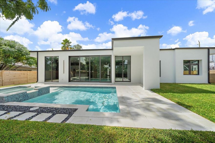One or more photo(s) has been virtually staged. Bold, modern, and effortlessly cool—this brand-new 2025 custom Sarasota pool home isn’t just a place to live, it’s a statement of style and intent. Crafted for those who crave a seamless blend of sophistication and function, the design fuses crisp contemporary architecture, light-filled interiors, and a private resort-inspired outdoor escape that feels both luxurious and livable. Just minutes from downtown Sarasota, Siesta Key, and the Gulf beaches, it captures the essence of coastal living with an urban edge and a distinctly modern flair, making every day feel like a staycation.

Positioned on an expansive 85’ x 117’ lot, the property offers rare privacy within fully fenced, professionally landscaped grounds. The backyard retreat centers around a heated pool and spa with a sun-shelf water feature, bordered by lush tropical greenery and a shaded alcove perfect for everything from quiet morning coffee to weekend gatherings under the stars. A north-facing orientation ensures comfortable sunlight year-round, while all-concrete block construction, impact-rated glass, and a durable roof provide enduring strength, security, and energy efficiency.

Inside, soaring 9’+ ceilings and walls of glass invite a flood of natural light across sleek, large-format porcelain tile flooring. The open-concept great room flows effortlessly into a chef’s kitchen that’s as functional as it is beautiful, featuring a dramatic waterfall island, Monogram appliances, induction cooktop, InstaHot water feature, and custom soft-close cabinetry. Every finish and fixture is new, refined, and intentionally chosen for everyday luxury—creating an interior that feels elevated yet warmly welcoming.

Spanning 2,726 square feet under air, the single-level layout offers 4 bedrooms and 3.5 baths, including three private ensuites—ideal for multi-generational living, extended stays, or hosting in style. The primary suite is a serene sanctuary with dual walk-in closets and a spa-caliber bath showcasing dual vanities, LED-lit mirrors, and a freestanding soaking tub within a glass-enclosed shower retreat. Each secondary suite mirrors that same attention to comfort and detail, while a front-facing bedroom with soaring windows creates a dramatic architectural focal point and a perfect flex space for an office, studio, or guest suite.

Designed for both beauty and practicality, the home features low insurance costs, a Flood Zone X location (no flood insurance required), and freedom from HOA or CDD fees. With flexible leasing options of up to 12 times per year, it’s as investment-savvy as it is lifestyle-rich—perfect for Airbnb, seasonal enjoyment, or full-time living. Located within the coveted Southside Elementary School district, it delivers both convenience and cachet in one of Sarasota’s most desirable neighborhoods.

Every element reflects thoughtful design and an appreciation for modern living—sophisticated, low-maintenance, and completely turnkey. For the discerning buyer, this residence offers the rare chance to own a new construction home that embodies Sarasota’s evolving luxury scene, where design meets purpose and relaxation meets refinement.

This is modern coastal living, elevated to an art form. Schedule your private tour today.