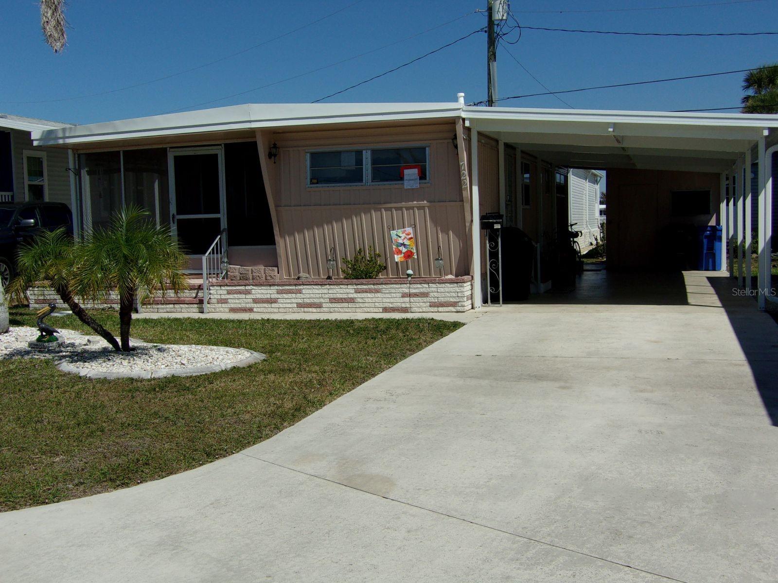 The lovely front porch on this home will give you many hours of enjoyment during those balmy Florida days and nights in this nice double wide home in Country Club Estates on the Island in Venice. Beautiful palm tree in the front and nicely landscaped to add to the view from within this home or street. New roof in 2024 and carport in 2025. Furnished and ready for a buyer to enjoy from day 1. The large carport is great for entertaining family and friends and long driveway for multiple car parking. This is resort style living. This beautiful community is located on venice island. Enjoy the heated pool with water aerobics and exercise classes. Country Club Estates has two clubhouses. Both with kitchens. One clubhouse has a stage for bands and performances, the other overlooks the waterway with rented boat slips for the residents. From the boat club to the book club you will probably find it here. Pickleball, shuffleboard, corn hole, DJ's for dances, neighborhood parades and scavenger hunts. Too many to list. This is not just a place to live--it is a lifestyle. Come see for yourself