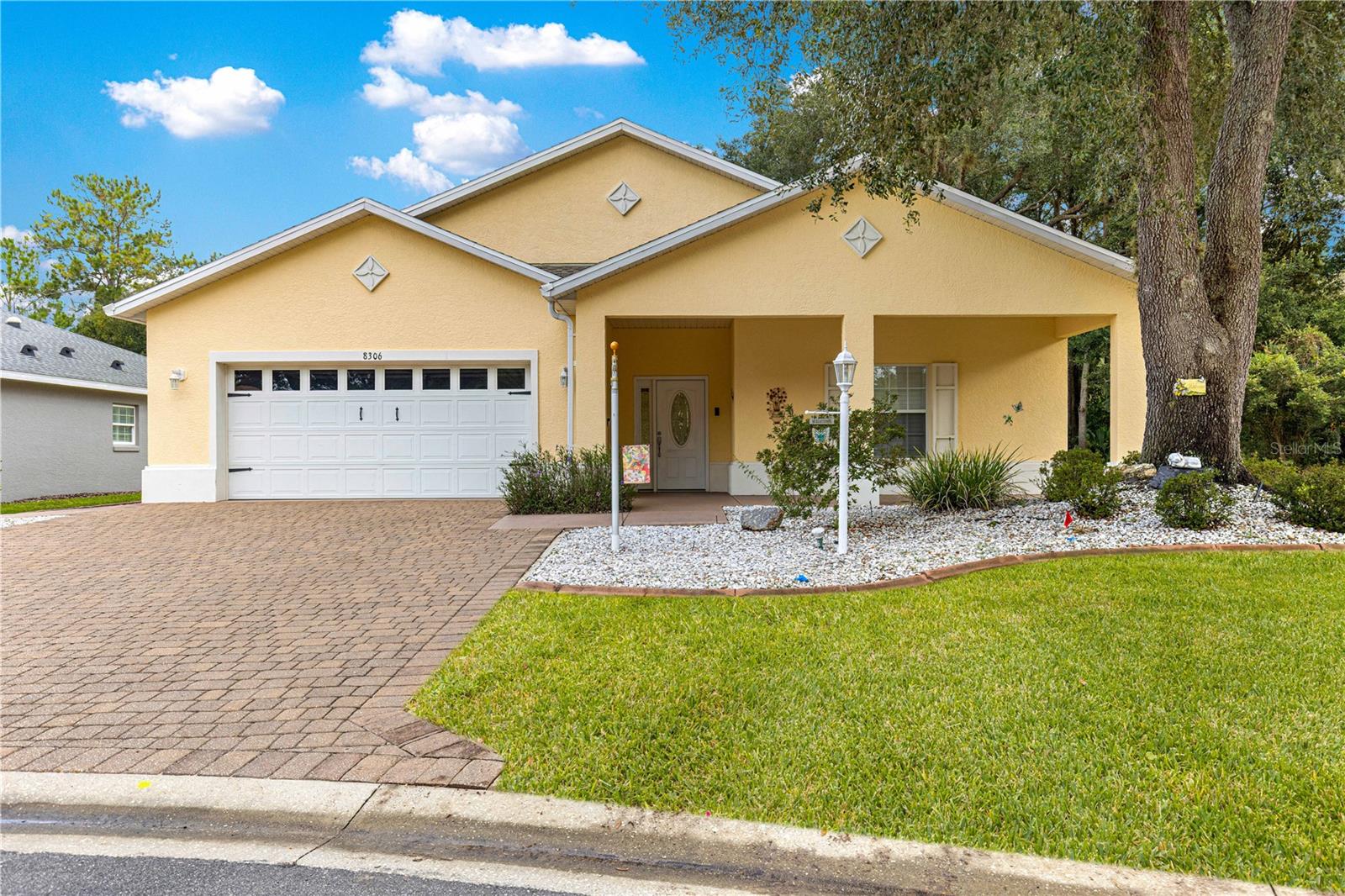 Indigo East Home with Casita: Welcome to this unique Hydrangea model tucked away on a quiet street in the sought-after Indigo East neighborhood of On Top of the World, Ocala’s premier gated 55+ community. This beautifully appointed 3-bedroom, 3-bathroom home features a spacious 2-car garage, a paved driveway, and a fenced backyard. One of the bedrooms, bathrooms, and kitchenette is located in a private guest casita—perfect for visitors who will enjoy the luxury of their own suite, separated from the main residence by a serene, screened tropical courtyard with raised stone planters, an outdoor bar and built in water fountain. Inside the main home, the chef’s kitchen boasts white cabinetry with crown molding, granite countertops, a large prep island, a generous pantry, a backsplash, and stainless-steel appliances. The open floor plan includes 18x18 tile flooring throughout the living areas, with vinyl flooring in the bedrooms for an updated look. Plantation shutters on all the windows and crown molding throughout the house provide a streamlined effect. One living room wall is floor to ceiling stacked stone with a built-in electric fireplace adding a unique touch. An oversized indoor laundry room offers built-in cabinets for extra storage and an extra sink. The primary bedroom features double walk-in closets and an ensuite bathroom with dual vanity sinks and a large walk-in shower. Step outside to your private backyard oasis, ideal for peaceful mornings or entertaining guests. Enjoy privacy from the lanai or relax on the patio surrounded by lush, fully sodded, and irrigated landscaping. This home also offers the convenience of curbside trash and mail service. A new roof was installed in 2022, and a new AC compressor was added in 2023. As a resident of Indigo East, you’ll enjoy all the amenities—including golf cart access to three shopping centers, two pools, Indigo Fitness Center, Indigo Community Center, walking trails, an outdoor fitness park, and a dog park.