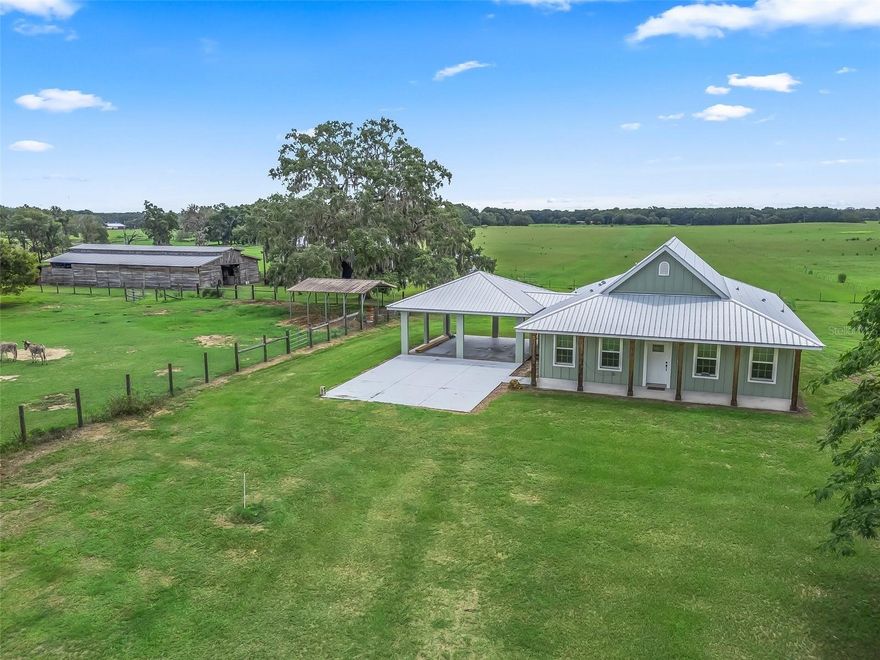 Modern Country Retreat on 25+ Acres – Built in 2023! Escape to tranquility, privacy, and wide-open spaces in this beautifully designed 2-bedroom, 2-bath home situated on over 25 high and dry acres. This country retreat is perfect for relaxed living as well as entertaining. Enjoy your morning coffee or evening sunsets on the inviting front and back porches. As you enter through the grand foyer, you'll be welcomed by a spacious open floor plan with tile flooring throughout. The kitchen features granite countertops and stainless steel appliances, offering ample counter space and complete with soft-close cabinets and drawers. The primary suite serves as a true sanctuary, boasting a luxurious walk-in shower, dual sinks, and thoughtful design for maximum comfort. This property is ideal for equestrian use or a gentleman's farm. It includes a massive 4-stall barn, with the potential for additional stalls, along with two pole barns. One pole barn features an RV hookup, while the other measures 30x50, making it perfect for storing all your equipment or recreational toys. Additionally, the 2-car carport is already prepped for an easy garage conversion and offers excellent potential to be transformed into a spacious third bedroom. Surrounded by nature yet conveniently located just minutes from the city of Bushnell, the Withlacoochee State Forest, and major roadways, this home seamlessly combines rural charm with modern convenience. If you need more land, the surrounding acreage is available, providing an opportunity to expand your vision and create your ultimate country estate. Don’t miss this rare opportunity—schedule your private tour today!
