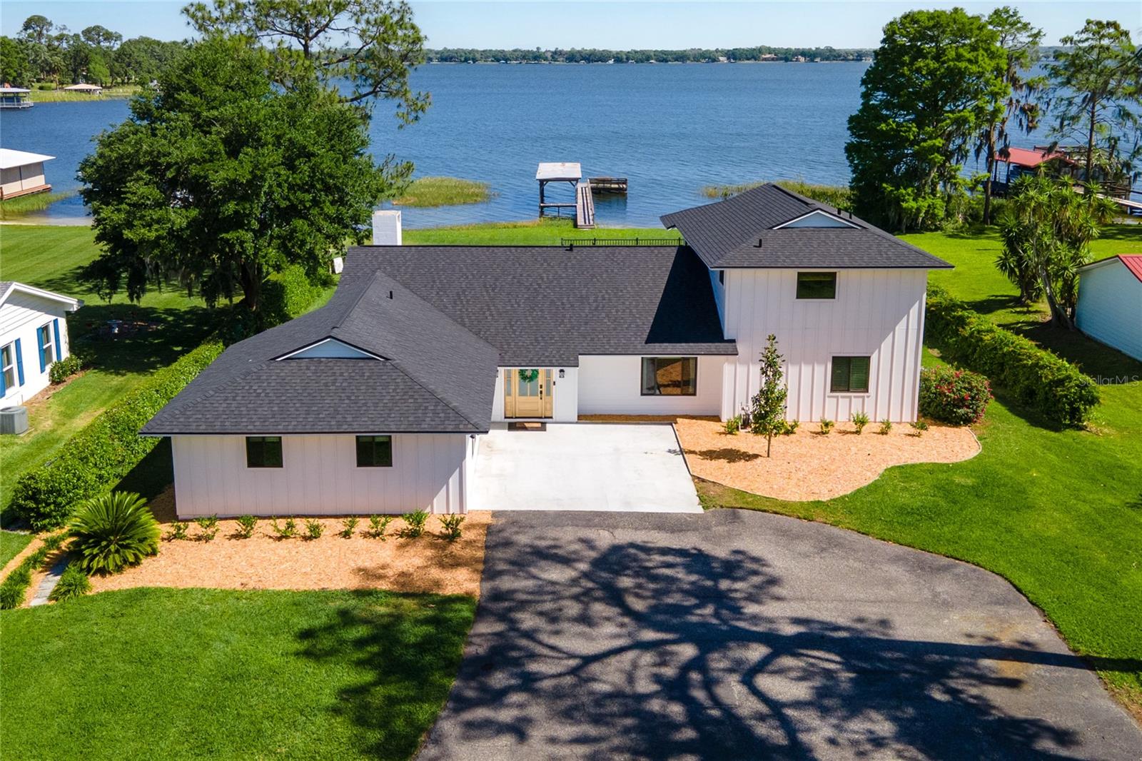 STUNNING LAKE DORA LAKEFRONT HOME IN TAVARES – COMPLETELY REMODELED & MOVE-IN READY! Sitting on over an acre of beauty, you will be stunned the moment you drive the long, peaceful driveway that leads to your impressive new HOME. Located in one of the most desirable spots directly on Lake Dora, this home has been meticulously updated from top to bottom, blending modern design with timeless charm. Let's start with a brand-new roof with certainteed lifetime architectural shingles with a storm shield peel and stick underlayment and a 15 year transferrable warranty! Step inside to discover brand-new luxury vinyl plank flooring throughout, with a gorgeous open-concept layout that makes the most of the perfect lake views. The completely remodeled kitchen is a chef’s dream, featuring a massive 15-foot center island, high-end appliances, and a custom coffee bar that could easily double as a bar area. The kitchen opens seamlessly to the living and dining areas, allowing for effortless entertaining with views of the sparkling waters of Lake Dora. Enjoy cozy evenings by the real wood-burning brick fireplace with custom built-ins, or step outside through the screened porch to take in the intimate lake views under a gorgeous tongue and groove ceiling. Bring the fishing poles and the boat to the dock featuring a 40 ft long boat slip...this truly is the best spot for the water lovers! The home features spacious guest bedrooms with a brand-new bathroom, and a massive laundry room that doubles as a convenient mudroom. The bonus room offers endless possibilities – perfect for a game room, man cave, or office area, complete with its own mini-split system for maximum comfort. Upstairs, the master retreat provides the perfect escape, complete with a private balcony overlooking Lake Dora. Enjoy hours of relaxation on the private Master Retreat balcony, while taking in the panoramic views including the fourth of July fireworks from over three cities. The master suite also boasts a large walk-in closet that has been customized and a newly updated ensuite bathroom with a custom stone shower. Additional features include brand new Pella energy efficient windows, hardie board siding with extra insulation for energy efficiency as well, along with top-of-the-line fixtures throughout. There is a well for irrigation and an advanced water purification system. New paint and cedar wood accents throughout give the home a modern yet rustic feel. The location is a boater’s paradise, with the Harris Chain of Lakes right out your back door, you can travel all the way to Jacksonville beach! Whether you're looking to fish, boat, or explore nearby Mount Dora or Tavares, this home offers it all. The calm waters of this specific location on Lake Dora are perfect for water sports, while the fishing is unparalleled. This is more than a home – it's a lifestyle. Live the lakefront dream and make this one-of-a-kind property yours today!