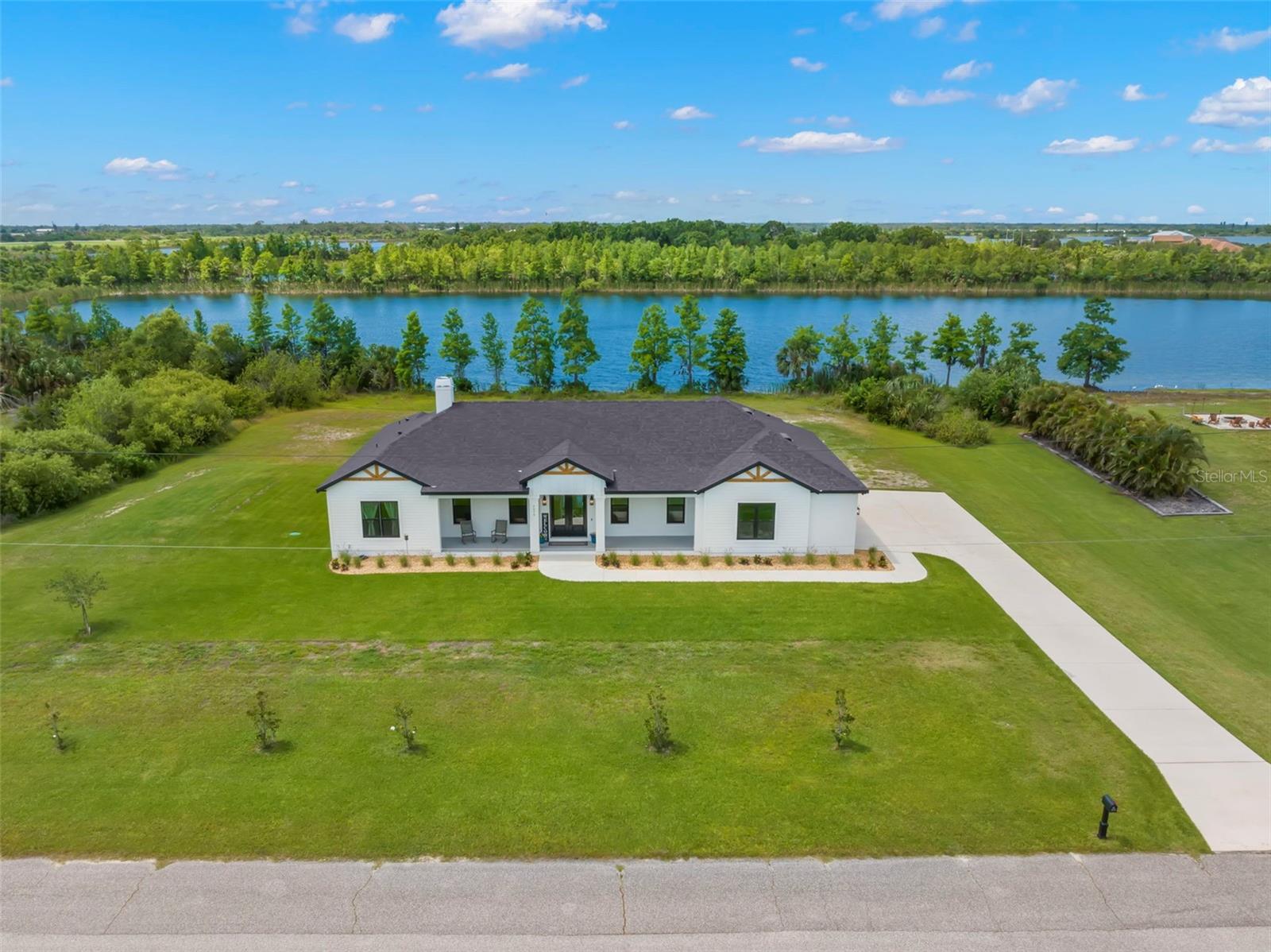 Lost River Preserve is a community with 82 homesites showcasing luxurious executive style properties on oversized lots that are surrounded by 900 acres of nature preserve. This community was featured on HGTV’s 100 Day Dream Home and has hiking trails, covered picnic areas, boat ramps and five private lakes where you will enjoy fishing, boating, waterskiing, kayaking and a variety of wildlife. You can add your own dock and lift if you desire! The community also allows for TWO-STORY detached structures to house all your recreational vehicles and has a lot where you can store your boat for no fee! Custom built by Chadwell Homes, this STUNNING home sits on a waterfront lot that is 1.75 acres and boasts impressive exterior features such as Hardie Board trim, wood gables, a covered entry and a spacious 3-car side-entry garage. The 3-way split floor plan provides privacy and includes 4 bedrooms and 3 full bathrooms. There are two primary bedrooms, each featuring en-suite baths, making this home perfect for multi-generational living. Elegance and comfort blend seamlessly as you enter through the double doors into the GREAT ROOM with 12’ ceilings, LUXURY VINYL PLANK flooring throughout and a fireplace that anchors the living room. The GOURMET kitchen is equipped with double wall ovens, a cooktop, pot filler, a backsplash with herringbone pattern and farmhouse sink with a window view. The white shaker style cabinets blend well with the natural wood cabinetry on the island and custom bar niche complete with open shelving and a wine refrigerator. Extend your living space into the covered rear porch that provides a relaxing area to enjoy gatherings with an expansive backyard which is easily cared for with the automated irrigation system. The yard is fully fenced, there are no backyard neighbors and the 220’ of water frontage provides you with private lake access for many water activities or to simply enjoy the serenity. Back inside, the primary bedroom has a double door entry and windows with motorized blinds. The en-suite is spa-like with a soaker tub, dual split vanities with linen storage, a water closet and a super-sized walk-in shower with seamless glass and shampoo/soap niches. The walk-in closet is large enough to house furniture for if additional storage is needed and has dual shelves. The secondary bedrooms are generously sized and share a hall bath that has tile installed to the ceiling, dual sinks and natural wood cabinetry. The second primary bedroom features a wall niche for furniture and an en-suite bathroom that boasts the same natural wood cabinetry, complete with linen storage. It also includes a walk-in shower adorned with floor-to-ceiling tiles and a seamless glass door. The laundry room has a sink with a vanity, extra storage complemented by countertop folding space, and shelves for hanging your items effortlessly. Additionally, it is connected to the primary bedroom, making this chore a much more enjoyable! Additional features and upgrades include timeless finishes such as black matte hardware and Quartz countertops throughout, a walk-in pantry with an electric outlet, double pane windows, hurricane shutters, oversized garage for larger vehicles, pull down attic access, plumbed for outdoor kitchen and the remainder of the warranties. There is a low HOA, No CDD and this home is not located in a flood zone. In addition to the private lakes, Cockroach Bay State Preserve is 5 minutes away which provides access to Tampa Bay.