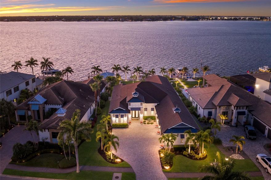 An extraordinary opportunity to own over 4,100 square feet of refined, single-level living on direct open water, complete with a private dock set against a breathtaking waterfront backdrop. Located within the exclusive, double-gated enclave of The Reserve at Harbour Walk on the Manatee River, this exceptional 2021-built estate offers the pinnacle of privacy, elegance, and coastal sophistication. From the moment you enter through the striking glass entry, you are welcomed by sweeping, unobstructed water views and a light-filled interior designed to impress. Professionally decorated with impeccable attention to detail, the home is offered furnished with an acceptable offer—presenting a true luxury experience. The grand vaulted living room showcases a sleek fireplace feature wall and a seamless blend of contemporary design and relaxed elegance. Expansive hurricane-impact windows and pocketing sliding glass doors seamlessly connect indoor and outdoor living spaces, while providing both beauty and peace of mind. The owner’s suite is a tranquil retreat, perfectly positioned to capture serene water vistas and complemented by a spacious walk-in closet. The spa-inspired bath features upscale finishes, dual vanities, and an oversized walk-in shower with a soaking tub enclosure. Guest accommodations are thoughtfully designed for comfort and privacy, each with adjacent baths. An expansive bonus room elevates the home’s entertainment appeal, complete with a wet bar, kegerator, and refrigerator—perfect for hosting while enjoying spectacular sunset views. A private office offers flexibility and can easily serve as a fourth bedroom. Outdoors, two generous lanai areas provide the ultimate waterfront lifestyle experience, enhanced by electric storm screens for added protection and comfort. A full outdoor kitchen, bar seating, and ample lounging space create an inviting setting to enjoy panoramic water views, vibrant sunsets, and abundant wildlife. The private dock is equipped with two boat lifts (30,000 lb and 10,000 lb), offering direct access to the Intracoastal Waterway and the Gulf, with waterfront dining and marinas just moments away. Further enhancing the home’s quality and resilience is a whole-house generator, ensuring uninterrupted comfort year-round. Residents of The Reserve at Harbour Walk enjoy a premier lifestyle with a guarded entrance, additional gated security, tennis courts, walking trails, kayak launch, playground, and observation pier. Ideally situated near I-75, upscale shopping and dining, world-renowned beaches, major airports, and IMG Academy, this residence embodies the very best of luxury waterfront living. This is a rare opportunity to own a fully curated waterfront retreat and experience Florida coastal living at its finest.