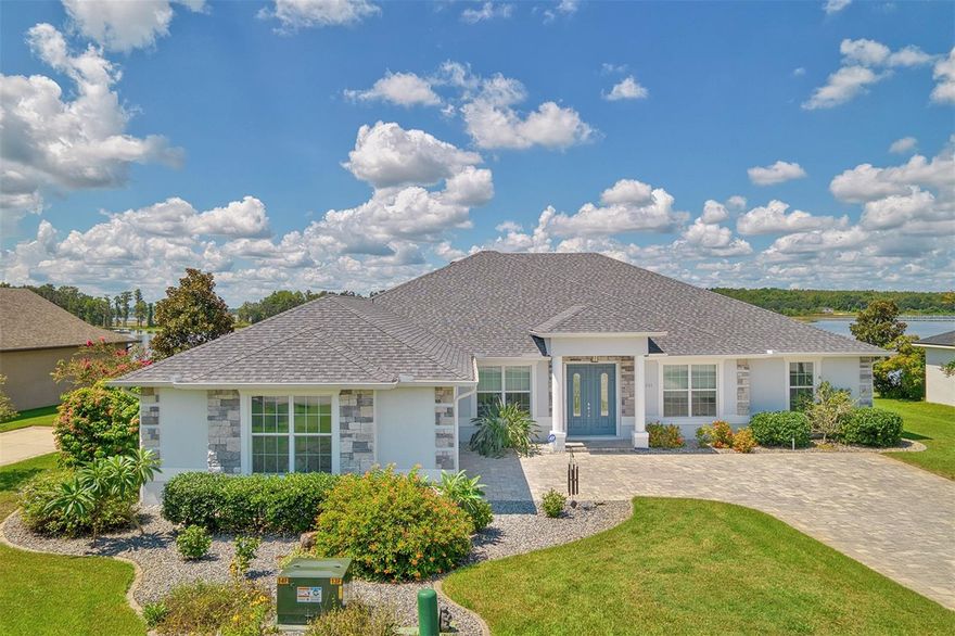 Welcome to your very own lakefront retreat on the crystal-clear, skiable waters of Little Lake Nellie-connected to the larger Lake Nellie! This custom-built gem blends luxury and comfort with stunning early morning owl moonsets and evening sunsets that you'll look forward to. Whether you're lounging on the screened patio or taking a dip in the nearly 40-foot solar-heated salt water pool with a custom 20-foot infinity edge, relaxing here comes easily. The emphasis is on safety with alarms on all doors leading to the lanai/pool area. You'll also appreciate the upgraded screen installed for reduced sun exposure. Inside, the home feels open and bright, thanks to a soaring 14-foot cathedral ceiling and a 24-foot wall of glass, made of 6 sliding glass doors that frame the lake like a painting.  Most rooms are handicap accessible and feature 8-foot tall doors, crown molding in every bedroom, and sleek tile flooring throughout (no carpet here!). This custom-built home provides a layout that feels both stylish and thoughtfully designed.    The kitchen is a dream with beautiful, functional, and elegant cabinetry, granite veined countertops to match the room, a wine cooler, slide-out pantry drawers, a wall-mount convection oven, a convection microwave, and tons of storage space. The spacious primary suite provides plenty of storage as well, with a custom walk-in room-sized closet, an ensuite with a glass-enclosed shower and dual sinks, as well as a peaceful office area with French doors to the lanai, overlooking the water. The second bedroom provides a charming window seat, while bedroom three has charming lake views with French doors to the lanai.  You'll also find a front office with double French doors-perfect for working from home-with room for a large desk and extra furniture. Smart upgrades throughout include spray foam attic insulation, a brand-new roof, and sun protection solar pool screen (2023), two HVAC systems, a Halo air purification system, two whole-house 5-micron water filters, gutters, a generous paver driveway, concrete landscape edging, lake-pump water irrigation, 2 terrace gardens, and a freshly sealed paver patio. Even the side-entry garage has been updated with a painted floor and service door.    And with space to build your own dock, this isn't just a lakefront home-it's a private, sunset-filled sanctuary where every day ends in beauty.