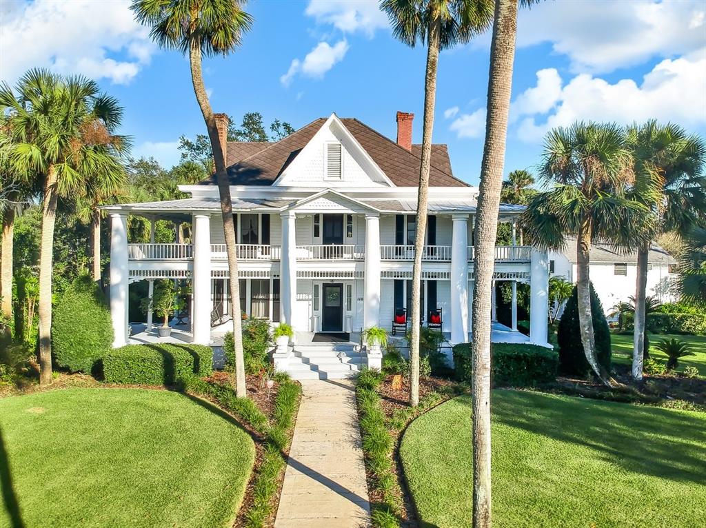 When it is noon in New York it is still 1904 in this Umatilla charmer! This impeccably cared for home, has been passed down from generation to generation from the early settlers of Umatilla. It is now available to be treasured by a new family and add a new chapter. This historically significant home is nestled on 1.8 acres of landscaped perfection. Appropriately updated to accommodate today’s lifestyle but with no detriment to the early 1900’s appeal. The grand entrance and wrap around porches on the 1st and 2nd floor move you back in time. You'll love the locally cut and milled heart of pine floors throughout the home. So many photo shoots of weddings, graduations and family gatherings have been taken here. This home has been updated with central air, but was designed to stay cool with 9 foot ceilings throughout and 8 foot wide hallways that are situated east-to-west and north-to-south to allow for natural airflow that pre-dates our modern cooling systems. This home provides all the amenities with a modern kitchen including a gas stove, important because you will be entertaining here! Formal dining room, reception room, sitting parlor and a master bedroom or office with Jack-and-Jill bath round out the first floor. Upstairs offers 4 bedrooms, including one a very large master suite and 2 more full baths. The third floor is unfinished space but about big enough to use as a ballroom, it is being used for storage of family heirlooms at present. An attic vent-fan will pull any warm air out lickity-split. Over the carriage house is a one bedroom / one bath apartment or mother-in-laws suite complete with a full efficiency kitchen and an outdoor deck that overlooks the rear gardens and grounds. (2 car spaces below available for parking) Full stand up crawl space under the entire house. There are land grants signed by presidents who could never imagine the recent Wedding venue which accommodated 250 seated guests. This home is spotlighted in the book Umatilla Florida, Images of America. This property has no limits just like the settlers that made it what it is today!!! Challenge yourself to exercise your vision and create a legacy. Most Furnishing are available as a private sale between Buyer and Seller.