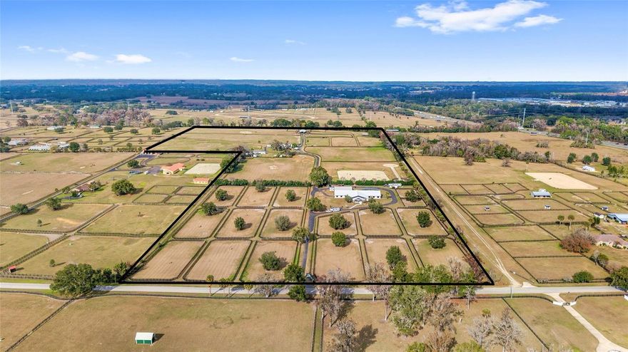 This fully built equestrian training and boarding facility is designed to support a professional program, offering the scale, layout, and infrastructure required for efficient daily operations. Located in Northwest Ocala’s highly sought-after Golden Corridor, this approximately 50-acre property is fully operational today while offering substantial room for expansion and long-term growth. The facility includes three barns totaling approximately 43 stalls, multiple on-site living quarters, and a complete training, conditioning, and recovery layout, thoughtfully designed to prioritize horse flow, labor efficiency, and functionality for serious operations. The main training barn features 14 oversized stalls with IDA rubber flooring throughout, insulated interior, updated electrical and lighting, new stall doors, industrial stall fans, and large ceiling-mounted HVLS fans for superior airflow and summer heat reduction, along with three cross-tie stations, a fly spray system, dedicated tack room, and laundry facilities. Attached to the main barn is an approximately 2,400 sq ft barn apartment with four private rooms, one bath, full kitchen, common area, designated office, storage, and direct barn access—ideal for on-site management or owner-operator living. Adjacent is a 40’ x 60’ open-sided conditioning and recovery barn featuring additional wash racks, a six-horse European-style walker with IDA rubber flooring, a shavings container with hydraulic roof lift, and space currently configured for therapy and spa use; equipment may be negotiated separately. Training amenities include a 200’ x 200’ LongWood riding arena, 150’ gymnastic pad, 60’ lunge circle, and 60’ round pen, all constructed with GGT footing and integrated sprinkler systems. The second barn is a ~4,700 sq ft center-aisle block barn with approximately 15 stalls and a new metal roof (2024), updated electrical and lighting, fly spray system, tack room with laundry and half bath, interior cross-ties with rubber flooring, and a covered double wash rack with hot water. The third barn is a wood-frame run-in barn with metal roof servicing the rear grazing pastures, allowing flexible turnout and shelter for additional horses. A 24’ x 50’ hay barn with new siding and additional storage sits adjacent to the second barn, serviced by a newly paved asphalt driveway. A brand-new 2025 three-bedroom, two-bath manufactured home provides additional on-site housing, along with climate-controlled storage in a heated and cooled Tough Shed and a 30’ x 50’ enclosed metal-roof structure currently used as an animal enclosure. The property is divided into 26 paddocks with automatic waterers and mature shade, including front turnouts with large shade trees, several paddocks with lean-to shelters and fans, and larger grazing areas to the rear. With established infrastructure, multiple living quarters, automatic water systems, and a prime Northwest Ocala location, this property offers exceptional efficiency and scalability for a professional equestrian operation while retaining the flexibility to evolve into a premier estate-level property over time