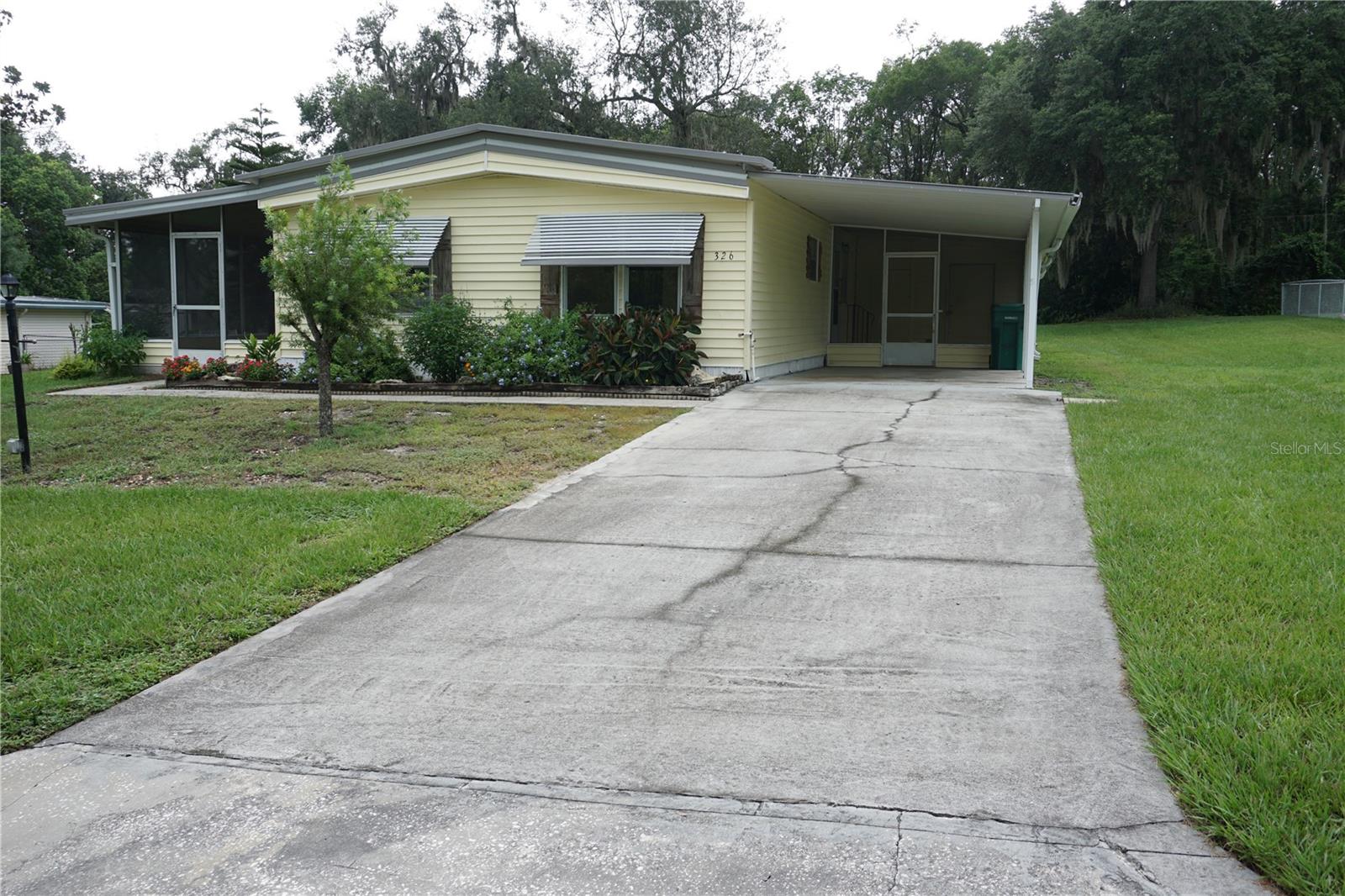 No Lot Rent, Own Your Own Land, just $200 a year HOA fee in this 55+ community. Freshly painted inside and new screening 7/16/25. This Doublewide is on .33 of an acre and sit's high and dry, no flood zone. Kitchen has Engineered Hardwood Floors, a double oven wall unit, a separate cook top, Stainless-Steel French door refrigerator with freezer drawer & a dishwasher. The formal dining room has a built-in cabinetry wall and there is a separate breakfast dining room with Engineered Hardwood Flooring. The living room is a nice size at 11' 7" x 19' 6" with sliding doors out to a covered 10' x 20' tile patio with new screening. There is also a 2nd screen room with tile where you enter the home off of the 12' x 21' carport. The bedrooms are a good size with primary bedroom having its own bathroom with walk-in shower. As a bonus there is a large, attached workshop area or could be used for storage. This location is surrounded by other good size lots, so you have some room around your home for more privacy. There is a community center and pretty surroundings with two lakes in the community. Don't miss being so close to The Villages with all it has to offer with its many dining, shopping & entertainment options. There is plenty of golfing nearby also.