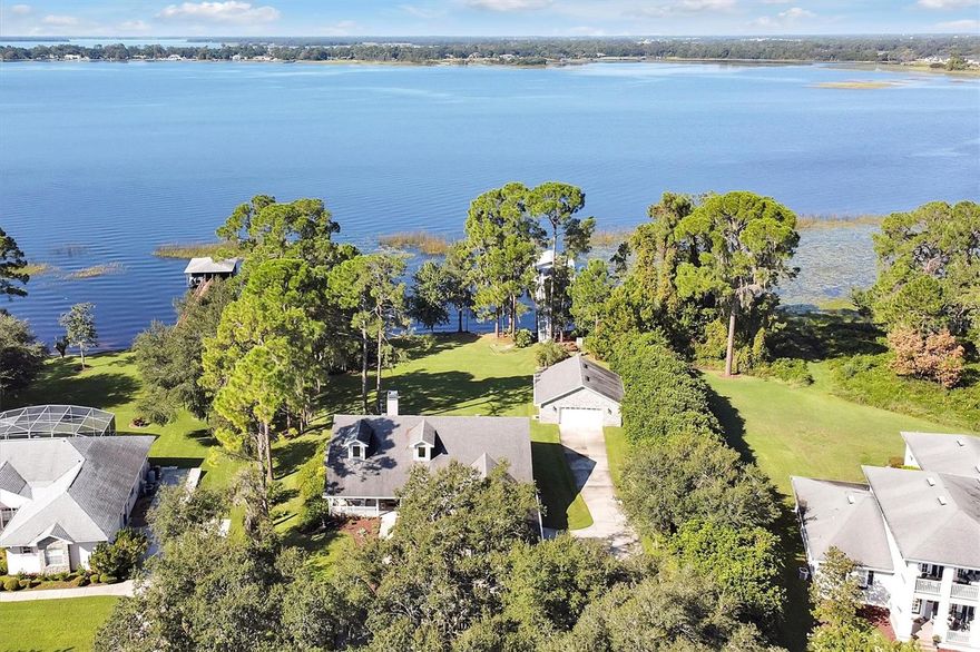 PRICE ADJUSTMENT BELOW APPRAISAL VALUE, LAKEFRONT LIVING ON THE CHAIN OF LAKES: This picturesque lakefront home is located in the highly desired community of NorthShore on Lake Lizzie and offers over 150’ of pristine lake frontage. Just step out, launch your kayaks and go for a paddle around the lake. Located on one acre complete with 125’ dock with boathouse, boat lift and a jet ski floating dock. Plenty of room for your outdoor furniture to entertain, watch the sunsets and fishing. Dock has water hookup, electrical supply, outdoor lighting and dimmable ambient lighting.
Your lake home features over 2,300 sq. ft. of living area. Open floor plan is great for entertaining family. When guests arrive they can utilize the gravel circle drive, enjoy the gorgeous view of the front yard with lush landscaping, beautiful Staghorns, and an outstanding view of the lake. Upon entering the home you will be stunned by the large stone wood-burning fireplace, 12’ sliding glass doors leading out to the covered lanai offering a great view of the lake complete with remote-controlled blinds. Vaulted ceilings with dormer windows offer plenty of natural light in the home for that warm, inviting feel. Upgrades to the home in the past few years include new luxury vinyl plank flooring, 5” baseboards, light fixtures, ceiling fans, New South high quality windows (picture windows along entire lake side of home), new owner’s bathroom with dual head walk-in shower and closet with custom built organizational system, solid core doors, new hardware, new water softener system, interior/exterior paint, low maintenance landscaping and gutter system. Kitchen includes granite countertops, soft close cabinets, pull-out cabinet shelving, cooking island, beverage area and breakfast bar. Did I mention over 1500 sq. ft. of garage space? Attached garage is over 650 sq. ft. – plenty of parking for your larger vehicles plus still plenty of storage and ladder access for storage above. The detached garage/workshop is 900 sq. ft. also with storage above and 220V hookup for your welder, etc. Enjoy building a fire in the fire pit located next to the lake, enjoy your favorite hot beverage and roasting marshmallows.
Exploring the chain of lakes includes six lakes to enjoy water recreation and nature at its best. Cypress, pine and oak tree shorelines, fishing and bird watching. Don’t forget the fun of skiing, wake boarding and swimming, pull up the boat at a favorite locals sandbar, or just enjoy a relaxing boat ride. Don’t settle for that small pond: Alligator Lake, 3,406 acres; Lake Lizzie, 792 acres; Brick Lake, 616 acres; Center Lake, 410 acres; Trout Lake, 273 acres and Coon Lake, 148 acres. And just a few minutes away is the Lake Lizzie Nature Preserve where you will enjoy hiking, biking, & horseback riding. Or just pull up your boat, kayaks or paddleboards and enjoy lunch at the public picnic area. Cruise thru the canals between the lakes and enjoy a large variety of birds and all type of wildlife making for a relaxing day on the water. 
The community of NorthShore offers a private boat ramp, walking trail and dock for all members of the community. Sellers are offering up to a $500 one year home warranty provided to buyers. Conveniently located within minutes to Lake Nona, Medical City, Orlando Airport, and just minutes to the beaches. Don’t miss this great opportunity, schedule your showing today…