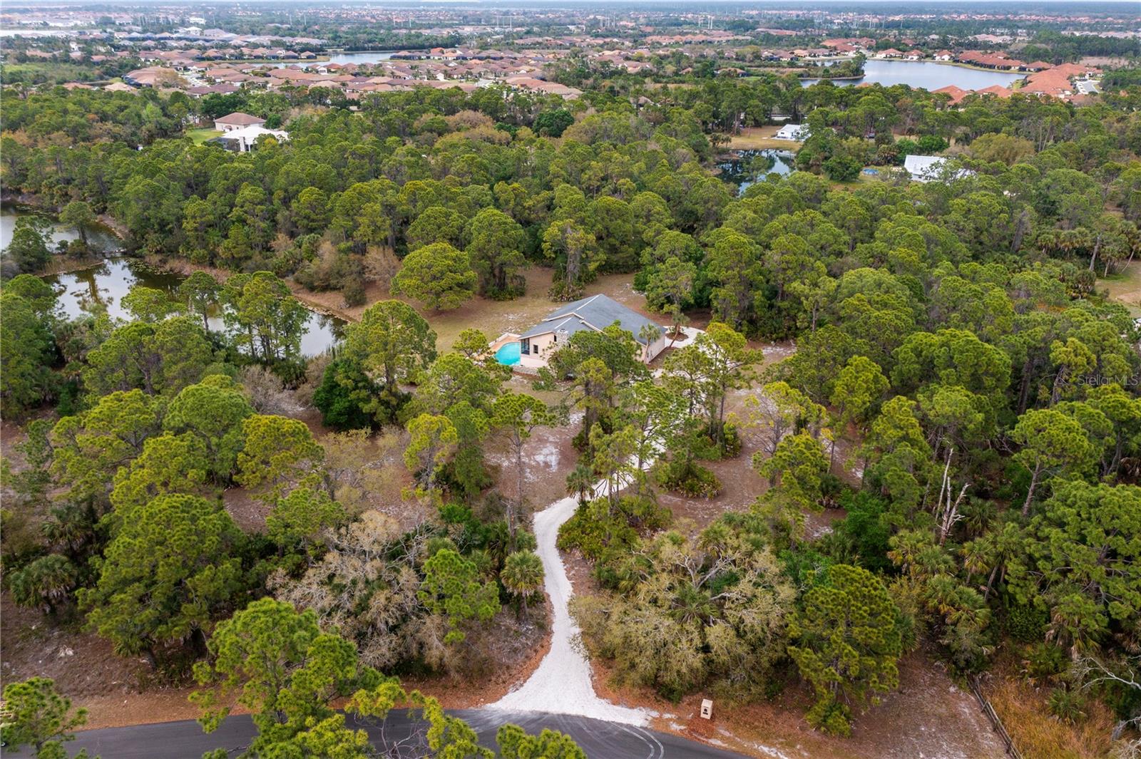 Private 6.75-acre retreat in Everglade Estates, Venice, FL, zoned OUE1 for agricultural and equestrian use. This 3,461 sq ft, 5-bed, 4-bath pool home sits in an X Flood Zone and offers serene lake views from the open kitchen, dining, and most rooms. Nestled among mature trees and natural landscape, it features a cedar plank cathedral ceiling, wood flooring, and a coral rock fireplace. The open kitchen includes stainless steel appliances, granite countertops, and a gas range island. The primary suite boasts a private balcony, steam shower, jetted tub, and cedar sauna. The 5 bedroom/Casita has a private entrance from the pool deck. A large lower-level flex room with wet bar and guest or IN-LAW suite is ideal for entertaining and opens up for you and your guests to enjoy the extra large and deep pool with a coral rock wall. The oversized 3-car garage offers plenty of storage space with an extra high bay door. Many important non-cosmetic improvements were made by the current owners in the past year; list available upon request. Minutes from I-75, Venice beaches, Historic Downtown Venice, and Wellen Park.
