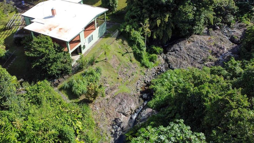 Riverfront Property Adjacent to El Yunque – Colinas de Cubuy, Canóvanas, PR

Discover a rare opportunity to own a unique riverfront property located in the Colinas de Cubuy neighborhood of Canóvanas, Puerto Rico, directly adjacent to El Yunque National Rainforest. This expansive property encompasses approximately five cuerdas of lush tropical land and is bisected by the Cubuy River, creating a private natural sanctuary with waterfalls, natural pools, and dramatic boulder-lined riverbanks.

The land is rich with mature vegetation, fruit trees, and flowering plants, offering privacy, shade, and a true connection to the surrounding rainforest environment. Cool mountain breezes, the sound of flowing water, and the proximity to El Yunque’s trails and natural features make this property especially appealing for those seeking a peaceful lifestyle immersed in nature.

The residence offers a flexible two-level layout that may function as a single large home or two units.
• The upper level includes approximately 800 sq ft of interior space, featuring a kitchen, living area, two bedrooms, and two bathrooms (one en suite). A large covered balcony expands the living space to over 1,500 sq ft, complete with a fireplace and river views.
• The lower level offers approximately 600 sq ft of interior space with two rooms, two bathrooms, a laundry area, and an open-air kitchen. With outdoor areas included, this level expands to over 1,700 sq ft and may be enclosed if desired.

Each bedroom is equipped with air conditioning, though the property benefits naturally from cooler temperatures due to its elevation and proximity to the rainforest. Recent improvements include updated windows, tile work, and A/C units.

Additional features include a separate storage building, a large cistern, a stable/horse area, and fenced land on the north side of the river. The expansive acreage and dual-unit configuration provide potential for multi-generational living, rental income, or a combination of personal use and investment.

Located in Canóvanas, this property offers convenient access to San Juan and the northeast coast while maintaining a distinctly rural, tranquil setting. Properties of this size with river frontage and direct access to El Yunque are increasingly rare.

This is a move-in ready opportunity for buyers seeking privacy, natural beauty, and versatility in one of Puerto Rico’s most unique settings.