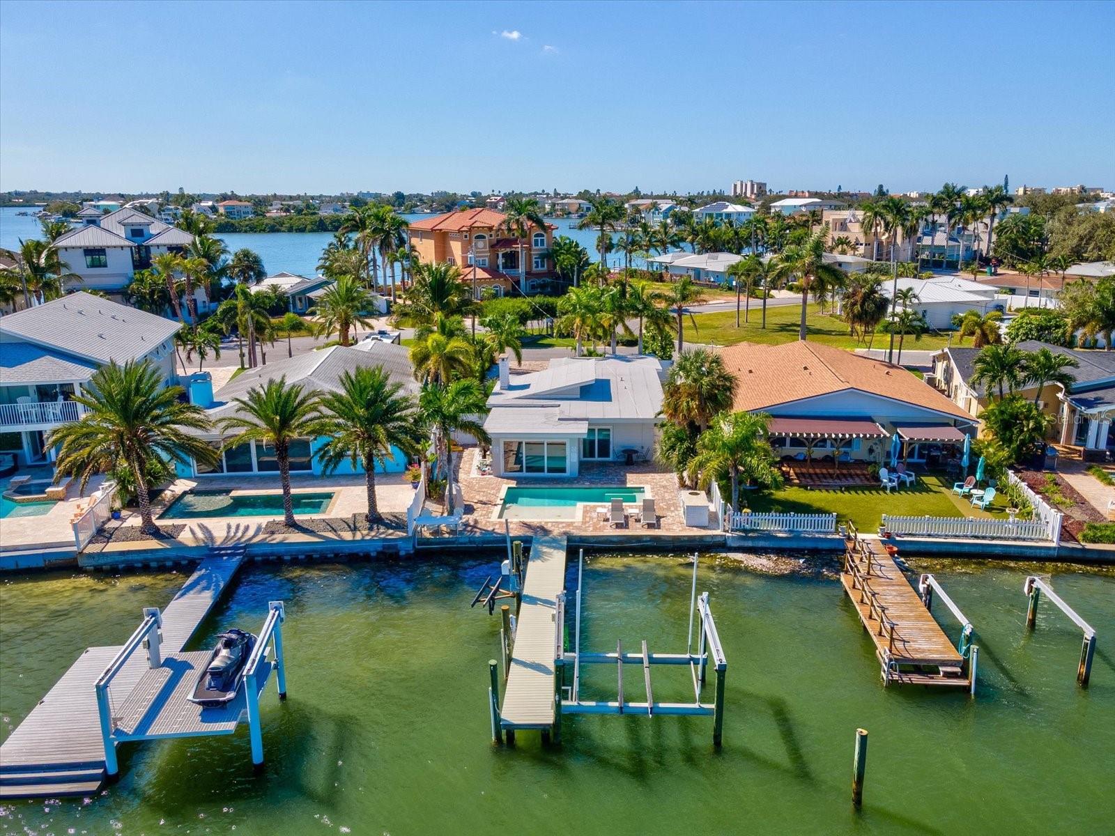 This beautifully updated coastal home offers the perfect blend of luxury, functionality, and peace of mind. Meticulously renovated post-hurricane, the property features impact-rated windows and doors, all upgraded to Cat 5 hurricane code standards. The open-concept layout showcases water views from nearly every room. The kitchen includes granite countertops, wood cabinetry, and vaulted ceilings overlooking the living area and pool deck. The primary suite offers stunning bay views, a walk-in closet, and a remodeled bath with a double vanity. The third bedroom comfortably fits a king-size bed, providing the perfect guest retreat. A dedicated bunk room and playroom combination make this home ideal for families—equally suited for full-time living or as a high-performing vacation rental. The property holds an active short-term rental license and has recently returned to the vacation rental market. Enjoy the Florida lifestyle from your private dock with a 16,000-lb boat lift and jet ski lift, perfect for quick access to waterfront dining or sunset cruises. Additional updates include all-new luxury vinyl flooring, new interior doors and hardware, fresh paint, and updated vanities. Located in a golf cart-friendly neighborhood close to parks, pickleball, dining, and just minutes to Clearwater Beach and downtown St. Pete. Plans for a new custom build are also available—see renderings in photos.