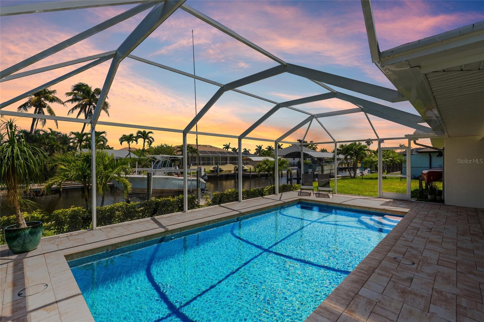Discover your nautical dream at this exquisitely renovated 3-bedroom, 2-bathroom Direct Sailboat-Access home, perfectly positioned in the sought-after waterfront heart of Southwest Cape Coral. Boating enthusiasts will rejoice with direct access to the Caloosahatchee River just 6 minutes from your private dock, complete with a meticulously maintained seawall and cap (2024) and updated 10,000 lb boat lift, making spontaneous voyages effortless. Step inside and be captivated by luxurious details—sleek new tile flooring seamlessly flows throughout the entire home, enhancing the coastal ambiance. The sophisticated kitchen features brand-new shaker cabinets, stunning quartz countertops, and a complete set of high-end appliances, ideal for gourmet entertaining or everyday enjoyment. Indulge in the spa-like bathrooms boasting full contemporary remodels, from designer sinks and fixtures to custom-tiled showers, all exuding modern elegance. The expansive living areas showcase stylish new ceiling fans, impactful lighting fixtures, and custom window treatments. Enjoy peace of mind and comfort with brand-new impact-resistant windows, sliding glass doors, and a gorgeous impact front entryway accented with elegant sidelights. Step outdoors to your private paradise, featuring a brand-new heated Pebble Tech saltwater pool (2024) encased in a stunning new pool cage. The inviting lanai, beautifully appointed with pavers, is perfect for hosting gatherings or relaxing in the tranquil surroundings. Mature landscaping, newly installed in 2024, frames the home beautifully, complemented by custom exterior awnings and a fully fenced yard. With every major upgrade thoughtfully executed—including a new GAF roof, HVAC system, tankless water heater, laundry sink, and garage door with opener—this home offers worry-free coastal living at its finest. Close to vibrant Tarpon Point Marina and Downtown Cape Coral, this meticulously updated residence is more than a home; it’s your gateway to living the ultimate waterfront lifestyle.