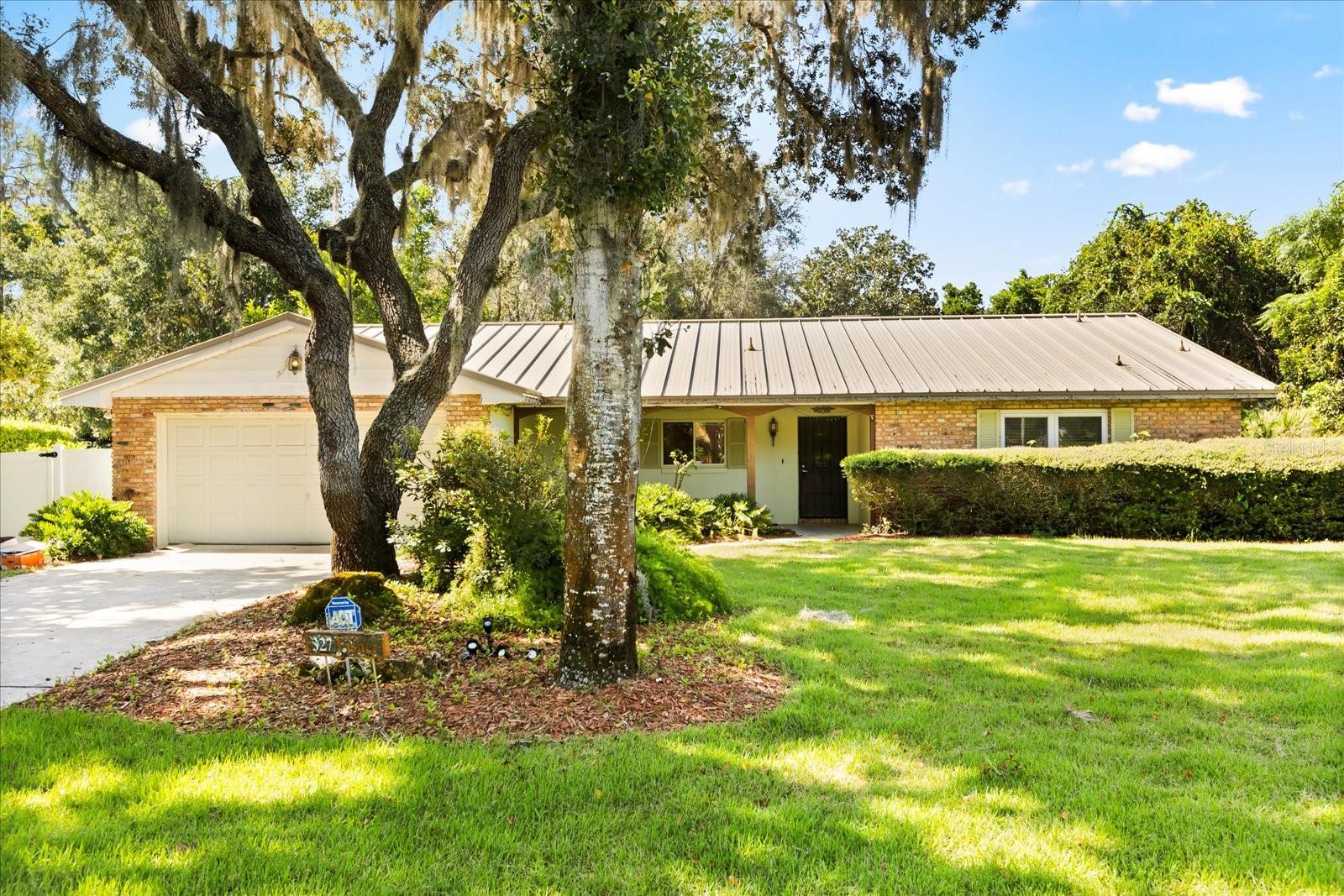 One or more photo(s) has been virtually staged. Discover this gem just minutes from charming Historic Downtown Mount Dora and beautiful Lake Dora. Located in the sought after neighborhood of Lake Dora Oaks this spacious home sits on an almost 1/2 acre gorgeous secluded wooded lot. No back yard neighbors! Entering the home you will be greeted by large open spaces. The living/dining room combo has lovely bamboo floors, a wood burning fireplace and has plenty of space to accommodate an extra large table for family gatherings. Off the living room is a huge family room that opens to the back yard and a large screened in back patio. The primary bedroom has an en suite bathroom and the other side of the fireplace. Bedroom #2 also has an en suite bathroom and walk-in closet. The kitchen has space for a breakfast table and has plenty of storage with a custom built pantry, custom cabinets with pull out shelves and two additional closets. Store all your tools in the 2 car garage. There is also a dedicated laundry room. The property is on a well system that will save you $$$ on keeping the lawn beautiful. Take a 5 minute walk to Lake Dora or a 5 minute drive to Downtown and enjoy all that Mount Dora has to offer.