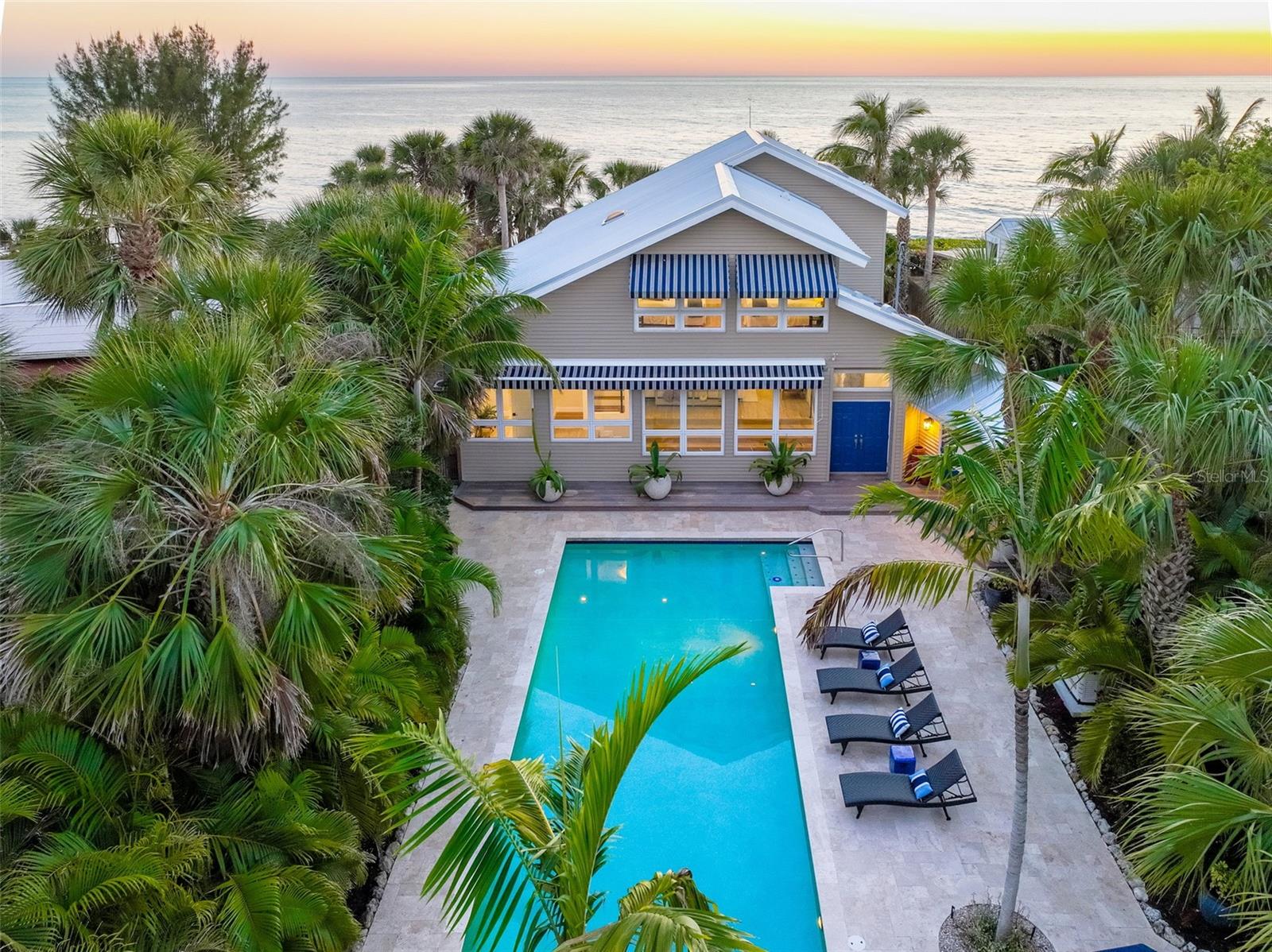 Delight in a captivating, private Gulf-front lifestyle with breathtaking views in this fully renovated Gulf-front estate perched 12 feet above the water on tranquil Point of Rocks at the southern end of Siesta Key. Tucked away on a stunning tree-canopied street, the 2-story main residence features five exquisitely remodeled en-suite bedrooms, plus an updated 1-bedroom, 1-bath guesthouse with an adjoining a 3-car garage. Hurricane-impact glass and a new metal roof provide peace of mind. New wood-look porcelain tile flows through most of the residence, including the expansive open great room with adjacent wet bar and dining area. The chef’s kitchen includes brand-new appliances and sunset views every evening, plus an island/breakfast bar, quartz counters, walk-in pantry and windows showcasing endless views of the azure water. Sliding glass doors in the dining room open to a sizable covered and open patio surrounded by palms and lush tropical foliage – the perfect setting for soaking in awe-inspiring Gulf and sunset vistas, gentle seaside breezes and the soothing sounds of rolling waves. A long staircase provides access to Point of Rocks’ flat limestone rocks, where you can hunt for seashells in the tide pools, spot dolphins and go snorkeling or kayaking to explore the abundant marine life. Inside the home, there is plenty of space for overnight visitors, with three guest bedrooms in separate wings, and a laundry room with a half bath accessible from the pool area. The great room’s expansive east-facing windows overlook the private courtyard’s abundant palms, flourishing gardens and saltwater pool. Upstairs, a serene retreat awaits in the impeccably appointed owner’s suite, featuring refinished hardwood floors, shiplap ceiling, built-in shelves and cabinetry, large walk-in closet with built-ins and walk-in shower. The bedroom also has an alluring sitting area with multiple windows boasting views of the enchanting seascape. A generous bedroom across the hall overlooks the courtyard and pool. Across the courtyard, there is a charming guesthouse, featuring wood-look porcelain tile, a full kitchen with shiplap ceiling, quartz counters and stunning backsplash, bedroom and bath with shiplap walls, and private patio with a barbecue area. Close to dining, shopping and world-renowned Siesta Beach, this one-of-a-kind seaside sanctuary offers an unsurpassed lifestyle for discerning buyers looking for their own piece of island paradise.