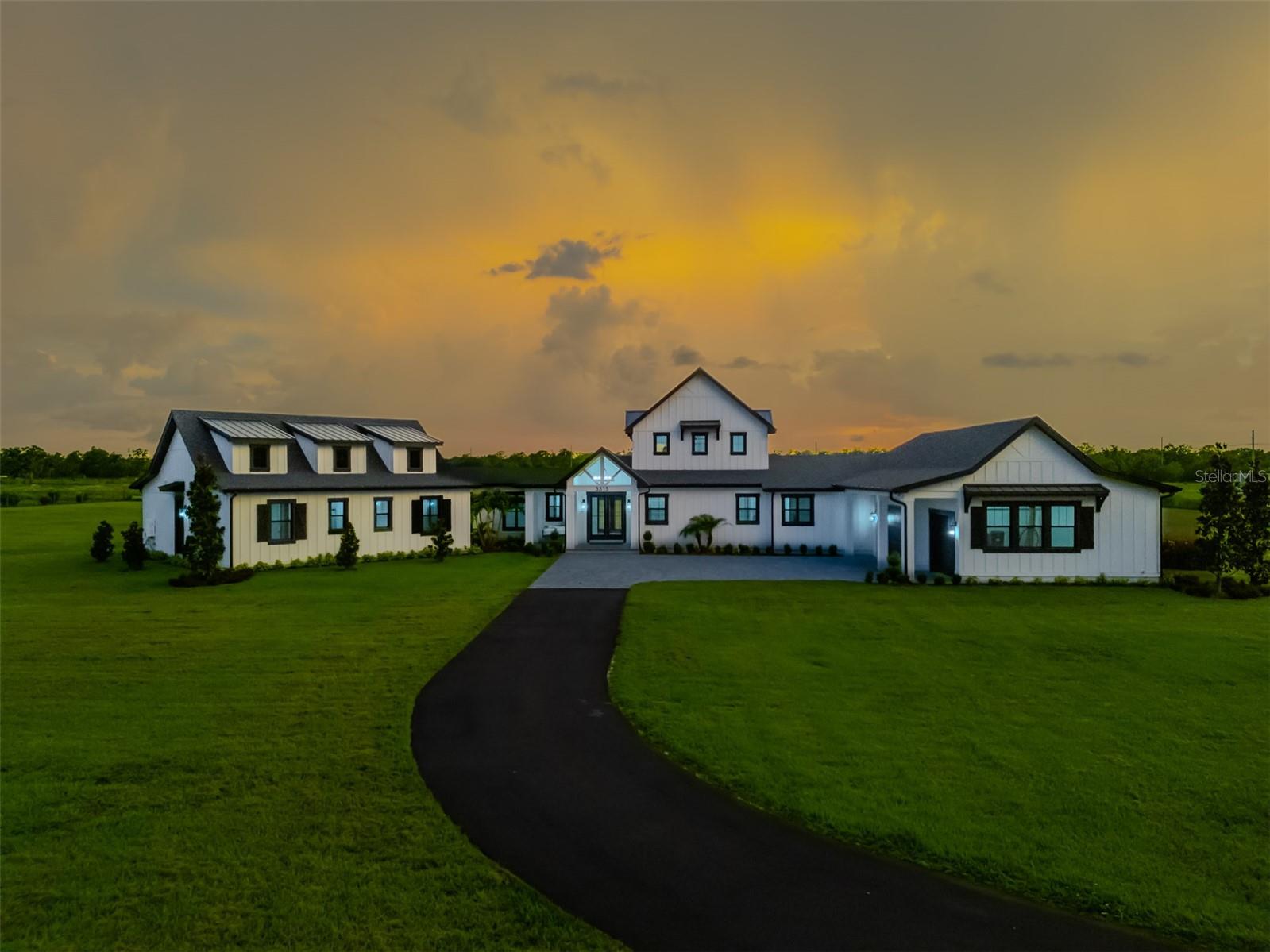 New Construction- Welcome to Big Sky Ranch! WOW... This is a stunning 4 br 4.5 bath, MODERN FARM-STYLE custom home! Truly one of a kind, this custom home demands attention and offers a spacious one level design. Step into the expansive family room and be instantly wowed by soaring 26 foot vaulted shiplap ceilings accented with exposed beams that draw the eye upward. A custom brick fireplace anchors one end of the room, flanked by built-in cabinetry and topped with a dramatic 10-foot ceiling fan. Natural light pours in through the picture windows and two sets of French doors. In the heart of the kitchen, a large T shape island provides ample prep space and seating for six. The kitchen is a chef's dream with high end appliances including a 48 in Wolfe range, double ovens, 2 farmhouse sinks, a pot filler and a wine cooler. Beautiful quartz countertops, subway tile backsplash, custom soft-close cabinets with pull outs complete the look. The dining area accommodates both casual and formal gatherings. Tucked away at one end of the house, the private primary suite offers a peaceful retreat, accessed through a charming galley off the dining room with exposed North Carolina barnwood beams. The primary bedroom features these same rustic touches, while the spa-like bathroom includes dual vanities, a freestanding soaking tub, a huge walk through shower with an overhead rain shower, two wall shower heads, a stunning glass block wall and SeaGlass flooring. The custom walk-in closet is just as impressive. Nearby, the spacious laundry room includes a sink and generous cabinetry for storage. Off of the kitchen, you'll find a large custom walk-in butler's pantry with a sink, abundant shelving and cabinetry, and double frosted glass doors. This wing also includes an office area and a mudroom with a built-in cubby system for the family. The family wing is located left of the foyer through a breezeway leading to three generously sized bedrooms, each with en-suite bathrooms and custom walk-in closets plus a bonus room perfect for casual entertaining or a playroom. Step outside to your backyard paradise with two large brick paved lanais and plenty of space for a pool. Enjoy your morning coffee on the cozy front porch swing . The oversized, attached 3 car side entry garage features epoxy flooring and adds to the home's practicality. Additional features include beautiful LVP flooring, LED can lighting and 8 inch nickel gap shiplap throughout. A 500 gallon propane tank, two tankless water heaters, Kohler faucets and toilets, leather dolomite countertops in secondary baths and laundry, a wireless surround system, custom closets throughout, generator pre-wiring, outdoor kitchen stub-out, and paver trim. A solar powered gate with keypad and exit sensors adds security and convenience. This house has great curb appeal with the brick paved driveway, the custom window shutters, professional landscaping, and that charming front porch swing. This home sits on nearly 5 acres, backs up to conservation land for added privacy, and is zoned for top-rated Randall and Newsome schools with a bus pick-up at the end of Powerline Road. With no HOA, you’re free to bring your boats, RVs, and horses—there’s even room to build a barn.
You will experience some of the most breathtaking sunsets Florida has to offer right here in your own backyard.