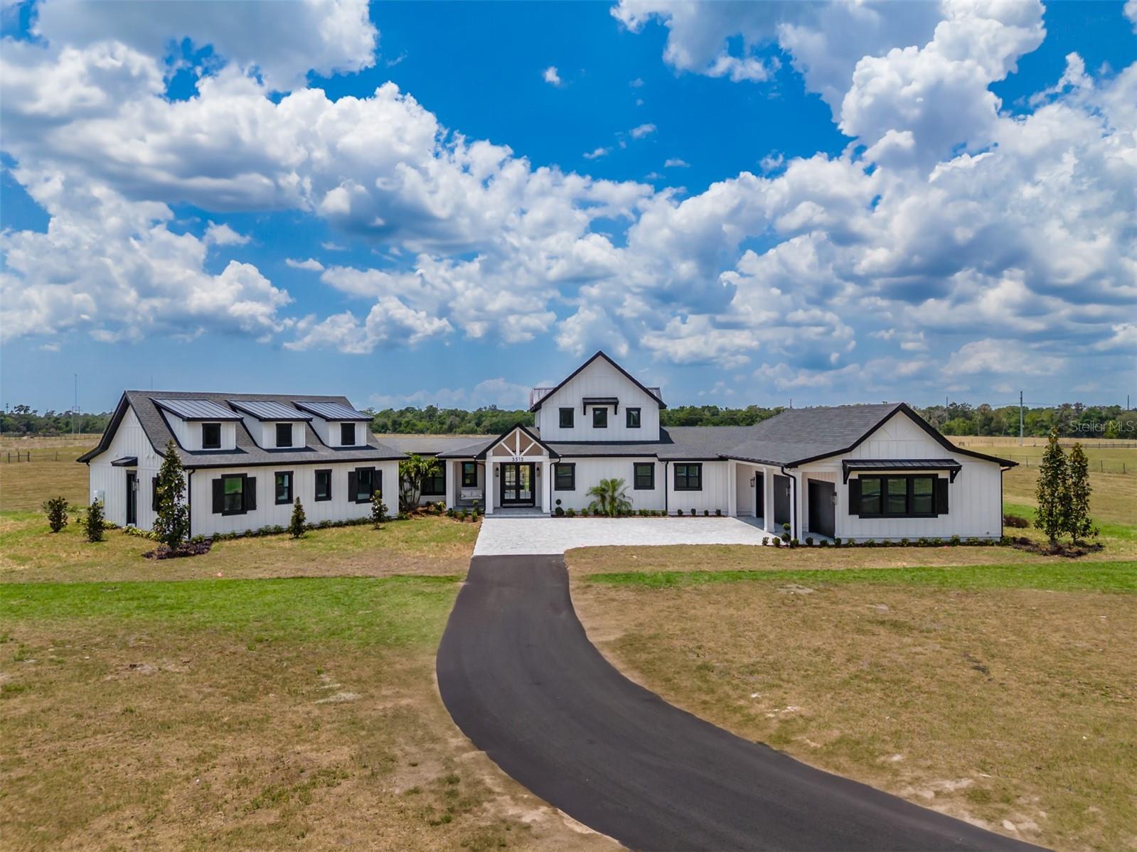 New Construction- Welcome to Big Sky Ranch! WOW... This is a stunning 4 br 4.5 bath, MODERN FARM-STYLE custom home! Truly one of a kind, this custom home demands attention and offers a spacious one level design. Step into the expansive family room and be instantly wowed by soaring 26 foot vaulted shiplap ceilings accented with exposed beams that draw the eye upward. A custom brick fireplace anchors one end of the room, flanked by built-in cabinetry and topped with a dramatic 10-foot ceiling fan. Natural light pours in through the picture windows and two sets of French doors. In the heart of the kitchen, a large T shape island provides ample prep space and seating for six. The kitchen is a chef's dream with high end appliances including a 48 in Wolfe range, double ovens, 2 farmhouse sinks, a pot filler and a wine cooler. Beautiful quartz countertops, subway tile backsplash, custom soft-close cabinets with pull outs complete the look. The dining area accommodates both casual and formal gatherings. Tucked away at one end of the house, the private primary suite offers a peaceful retreat, accessed through a charming galley off the dining room with exposed North Carolina barnwood beams. The primary bedroom features these same rustic touches, while the spa-like bathroom includes dual vanities, a freestanding soaking tub, a huge walk through shower with an overhead rain shower, two wall shower heads, a stunning glass block wall and SeaGlass flooring. The custom walk-in closet is just as impressive. Nearby, the spacious laundry room includes a sink and generous cabinetry for storage. Off of the kitchen, you'll find a large custom walk-in butler's pantry with a sink, abundant shelving and cabinetry, and double frosted glass doors. This wing also includes an office area and a mudroom with a built-in cubby system for the family. The family wing is located left of the foyer through a breezeway leading to three generously sized bedrooms, each with en-suite bathrooms and custom walk-in closets plus a bonus room perfect for casual entertaining or a playroom. Step outside to your backyard paradise with two large brick paved lanais and plenty of space for a pool. Enjoy your morning coffee on the cozy front porch swing . The oversized, attached 3 car side entry garage features epoxy flooring and adds to the home's practicality. Additional features include beautiful LVP flooring, LED can lighting and 8 inch nickel gap shiplap throughout. A 500 gallon propane tank, two tankless water heaters, Kohler faucets and toilets, leather dolomite countertops in secondary baths and laundry, a wireless surround system, custom closets throughout, generator pre-wiring, outdoor kitchen stub-out, and paver trim. A solar powered gate with keypad and exit sensors adds security and convenience. This house has great curb appeal with the brick paved driveway, the custom window shutters, professional landscaping, and that charming front porch swing. This home sits on nearly 5 acres, backs up to conservation land for added privacy, and is zoned for top-rated Randall and Newsome schools with a bus pick-up at the end of Powerline Road. With no HOA, you’re free to bring your boats, RVs, and horses—there’s even room to build a barn.
You will experience some of the most breathtaking sunsets Florida has to offer right here in your own backyard.