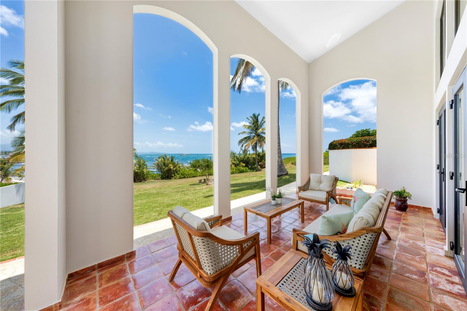 ***SOLD*** Introducing 17 Surfside, an expertly renovated 3-story beachfront home completed in 2023, featuring an unparalleled opportunity to indulge in luxurious living on the sand, while enjoying breathtaking views of the Caribbean Sea and all that Palmas del Mar has to offer. Inspired by the coastal lifestyle of the tropics, this oceanfront residence has undergone a lengthy renovation and full design. Stepping through the front door, one is instantly impressed by the open and dynamic layout, which maximizes natural light via the home's broad floor to ceiling glass windows. Warm yet illuminating undertones within the spaces redesign, elegantly highlight the exquisite wooden craftsmanship and sweeping arches throughout. With a total of 5,847 Sq.Ft. interior and exterior living, sitting on just about a half an acre rolling onto the sand, this beachfront retreat offers 3 generously-sized bedrooms all with bathrooms ensuite, evenly distributed throughout the home. The ocean-focused primary suite affords a California king facing the water, as well as a double expansive lounge with trundle bed and dual walk-in closets. The spa-inspired ensuite bathroom, complete with soak tub, walk-in shower and brushed slate fixtures are all curated towards ensuring you a pampering experience. Wake up and walk out onto your terrace into spectacular endless ocean views as well as the Island of Vieques. The entry level of this remarkably reimagined home features a laundry and mudroom, open elevated kitchen, and dining area. Sliding glass doors lead from your kitchen and dining to a covered patio perfect for hosting gatherings or simply relaxing while enjoying the panoramic ocean vistas. The gourmet kitchen features an eat-in bar, top-of-the-line custom appliances, functional cabinetry, and floor plan that offers both usable workspace and ideal gathering area for family and friends. Stairs up towards your guest room suite, fitted with bunk bed, skylights and full wrap around ocean view terrace, is sure to have anyone who stays, fall in love with the privacy. The open air ground level living and entertainment room boasts 20 ft ceilings and floor-to-ceiling eastern facing vistas that frame the panoramic views, creating a seamless connection between the graciously designed indoors and the lush exteriors. Outdoors, this estate is designed to embrace the sun. Step out onto your private terraces or rolling green areas, where you can bask in the sun, entertain guests, or simply relax while enjoying pink and purple sunrises and sunsets that Palmas del Mar is famous for. Fully furnished and being sold turnkey, this ocean home offers direct access to the sandy beach just steps from your front door. Immerse yourself in the refreshing waters, take leisurely walks along the shoreline, or engage in your favorite watersports and activities. Located within the gates of Palmas del Mar, residents of 17 Surfside enjoy access to a range of exclusive amenities, including tropic beaches, multiple golf courses, tennis courts, restaurants, private school, as well as Yacht Club & Marina. The community's meticulously landscaped grounds and 24-hour security provide a safe and serene environment for all residents. Annual HOA: $992.