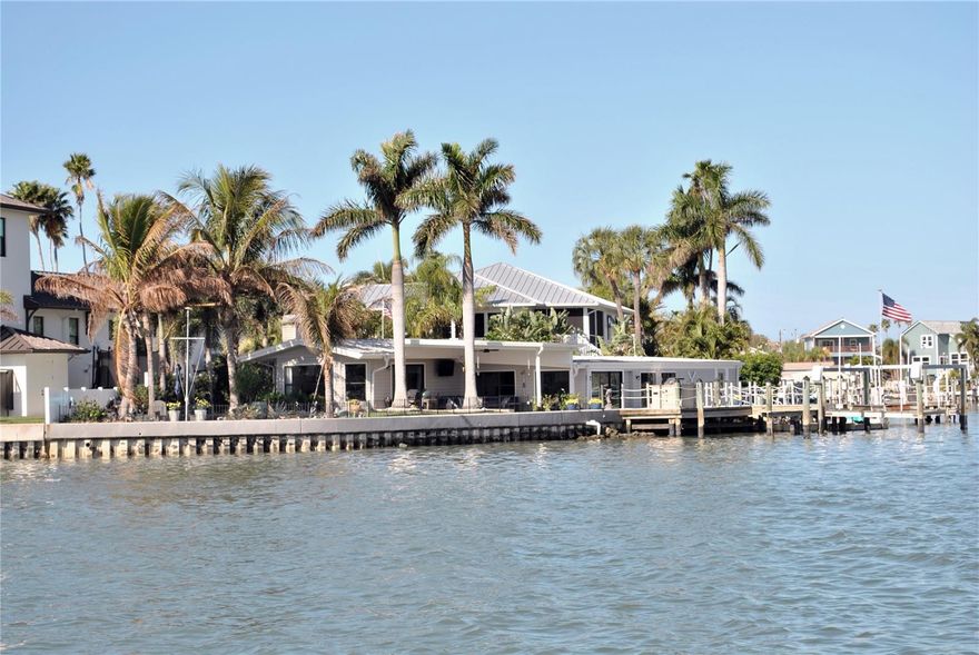 Bright and beautiful aptly describes this pristine 2 bedroom, 2 bath, waterfront home on a secluded cul-de-sac lot in the highly sought after golf cart friendly Indian Rocks Beach. Indian Rocks Beach is one of Florida's most desirable beach communities and is known for it's stunning white sand beach and its friendly, easygoing charm. This coastal home has an amazing 140 ft sea wall (2014) that opens up the home to a stunning water view from nearly every window and the coastal inspired backyard and outdoor patios.  This well laid out open floor plan boasts a welcoming living room, dining room, and a large kitchen with glass mosaic backsplash, quartz countertops, solid wood cabinetry, new stainless steel induction range, dishwasher and stainless steel refrigerator. The primary bedroom suite is spacious and split from the other generous sized bedroom for privacy and has an amazing water view. The hurricane rated sliders from the dining room and living room open up to the awesome backyard featuring a custom paved patio with an outdoor shower, a putting green, outdoor grill and dock; creating a seamless blend of indoor/outdoor entertainment living.  There are several sitting areas in the backyard oasis that are enhanced by the stunning flower gardens and natives plants.  Enjoy your morning coffee on your patio and say "hi" to the dolphins who visit every morning around 7 am. The  dophins come back around 7 pm with the tide. This home has a large deep water slip suitable for a sailboat, a dock with a 20,000 lb boat lift and a floating platform to launch your kayak. There is plenty of storage in the 1 car garage and utility area of the home. This delightful light and bright home is move in ready with tasteful touches such as crown molding, 6" base boards, pristine wood-look tile floors, and neutral color tones all achieved with elegance and great taste. The metal roof was installed in 2015. This home also has reclaimed water for irrigation. Indian Rocks Beach also allows short term rentals. The location is truly amazing; jump in your golf cart to nearby shops, restaurants, and the beach that are a short walk or bike ride away.  If you love the outdoors there are many recreational activities, from golf to fishing, kayaking and boating. Couple this with excellent schools, pristine beaches and all that fabulous Indian Rocks Beach has to offer and you have the ultimate Florida lifestyle home.