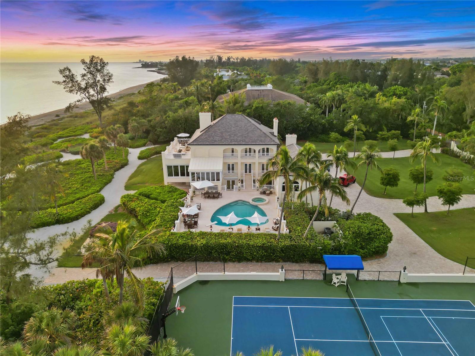 Imagine your very own resort-like estate in the heart of the most sought after community in all of Sarasota! Sanderling Club is nestled on the south end of the world renown barrier island of Siesta Key. This ultimate beachfront experience is the true definition of living in paradise. This property offers the most exquisite home on almost 4.5 acres with over 300 feet of beachfront. The primary residence with over 8,600 square feet of living space is ideally positioned, capturing the amber skyline and emerald green waterways of the Gulf of Mexico from every angle. The interior design of this magnificent home is perfect for entertaining with the main living areas and spacious dining room facing the west to enjoy Southwest Florida sunsets every evening.   The custom kitchen features Rutt cabinetry, a large island with plenty of seating, Wolf and Sub-Zero appliances, gorgeous marble countertops accented by brushed gold hardware creating an elegant experience in the heart of the home. The family room creates a warm inviting feeling as soon as you enter the space. The attention to detail throughout including custom moulding, built in shelving, views of mature tropical foliage, and the sparkling pool create such an incredible ambiance and place to create many fond experiences with family and friends. The home office, only accessed through a secret hidden door, makes working from home a pleasure. This property is meticulously well maintained with many recent updates to the main house including: brand new roof installed in 2023, new custom kitchen, beautifully renovated bathrooms, new engineered walnut flooring throughout, elegant marble flooring, custom wood millwork, a butler’s kitchen, LED lighting throughout, newer HVAC systems and ductwork, elevator, exterior patio railings, gated entry, Smart Home Wi-Fi enabled automation, and brand new hurricane impact window and doors installed in 2023.  The private owner's suite is on one level featuring a spa-like bathroom with tranquil water views. The suite offers a private waterfront terrace and dual custom closets. The two guest suites also offer breathtaking views.  The lower level features another full service kitchen, an additional guest space or gym, two full bathrooms, a steam room, a sauna, an expansive garage, and additional storage room. The second kitchen is easily accessible to the salt water pool and spa, a lighted tiki hut, outdoor fire pit, tennis courts, and a new paved drive space. The guest house with over 2,300 square feet of living space was built in 2007 and is a kayaker's dream located on Heron Lagoon with 316 ft of waterfront . With an open great room plan and high ceilings your guests will feel like they are in a tropical oasis. The guest house has a full kitchen, 2 en-suite, bedrooms, a large screened in terrace, and a large deck leading out to the boat dock. The dock is ideal for launching your kayak or canoe. Relax and simply sit on the dock and enjoy the sounds of birds chirping and the sound of palm trees swaying in the wind. This estate is within the guarded & gated community of Sanderling Club. The community offers amenities such as: a beach club, tennis and pickleball courts, Paul Rudolph-designed beach cabanas, playground, and dockage on the bay.