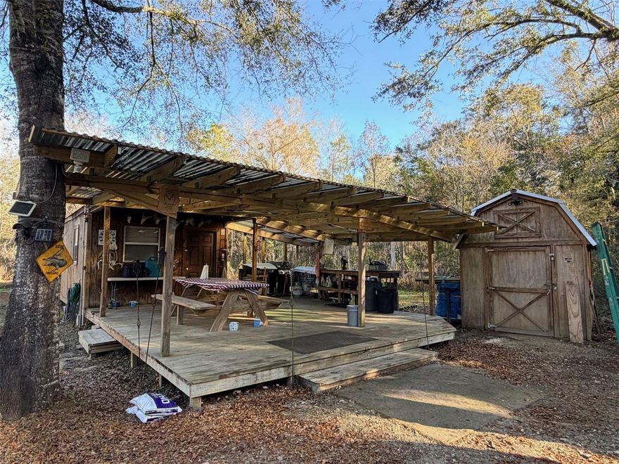 Tucked deep in the woods of Otter Creek, this remote 80 acre hunting and recreational tract offers true Old Florida seclusion, located approximately 4 miles off the main highway. Surrounded by natural timberland, the property is loaded with wildlife, including deer, hogs, turkey and documented bear activity, making it an ideal private hunting retreat or off-grid getaway. The land is set up as a turn-key hunting camp, featuring a 12x30 cabin with a sleeping area, kitchen storage and a dedicated toilet room. Attached to the cabin is a spacious 20x22 covered deck with an outdoor kitchen setup, perfect for camp cooking and gathering after a day in the woods. Just behind the cabin is a separate bath house with a hot water shower. Additional improvements include two sheds, one of which is outfitted as a bunk house with a mini-split A/C unit, providing extra sleeping space for guests or hunting partners. Two ponds are located near the campsite, adding both water and wildlife attraction. The seller is including multiple tree stands, an elevated hunting blind and several feeders, along with a New Holland tractor and attachments to maintain roads and food plots. Materials for a future pole barn are also already on site. This is a true off-grid property with no utility power available; current use is via generators and solar power could be added by the next owner. Despite its secluded setting, the property is conveniently located about 35 minutes from Chiefland for shopping and dining or Cedar Key and the Gulf. If you’re looking for privacy, self-sufficiency and a ready-to-use Florida hunting camp, this rare large-acreage tract delivers.