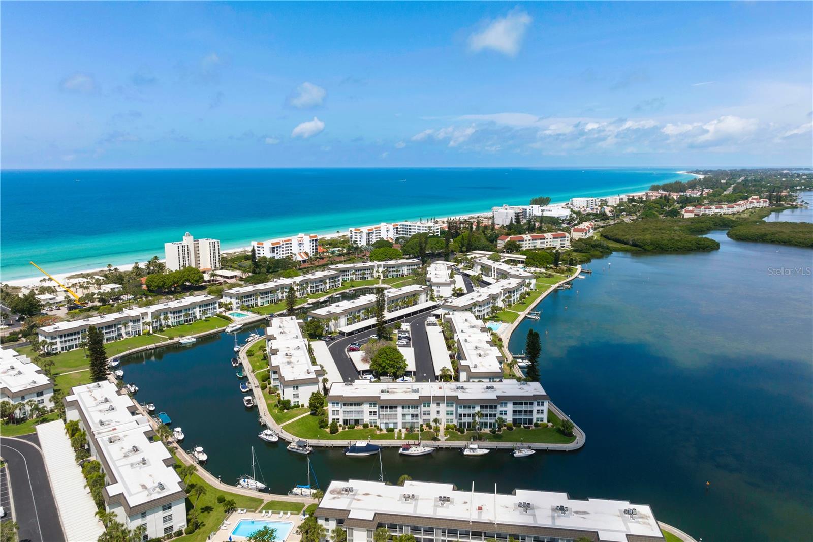 NEW PRICE IMPROVMENT! Looking for your piece of paradise on the Suncoast of Florida? Don't miss the opportunity to own in the coveted beach to bay gated community of Longboat Harbour on world famous Longboat Key. Perfect for full time or seasonal residents and investors, take the elevator to this second floor two-bedroom two bath condo Turnkey, with new luxury vinyl plank flooring- just bring your suitcase and enjoy. Nearly every room in the home offers water views. Sip your morning coffee or evening beverage from the covered and screened lanai overlooking the tranquil boat basin and canal. A large closet on the lanai gives you loads of additional storage space. The bright and airy great room opens to the lanai through glass sliding doors which allow the coastal breezes to flow through. The kitchen features a pass through to the family room space for a café table and plentiful cabinet storage and countertop prep space, Separate coffer bar area, Stainless Appliances. .The new beautifully appointed master suite enjoys views of the boat basin and canal. The master bath has quartz countertops, a large walk-in shower and is complemented with The washer and dryer included. The guest bedroom has a partial view of the bay, and the second updated bath has a tub/shower combination. This unit comes with one assigned covered carport space. This waterfront community is known for its amenities such as gated entry, manager on duty, tennis, pickleball, four heated pools, dockage, putting green, fitness center, game room, clubhouse, woodworking /Art room, grills and more. For boaters there is sailboat water, no bridges to the bay and boat slips for rent. Imagine having your boat moored up to a space that has easy access to the bay. Longboat Harbour offers a private deeded beach access (4415 Gulf of Mexico), complete with beach house facility that includes restrooms, showers and reserved parking. Shopping and dining are only minutes away on Longboat Key or St. Armands Circle or travel over the John Ringling bridge to downtown Sarasota and the Bayfront to enjoy the arts, theater, festivals, restaurants, shops and Selby Botanical Gardens on the bay. Everything you need for resort-style living is found here. Come preview this beautiful condominium. Priced to sell fast. Schedule your showing today. New Roof replacement is in process. The assessment has been paid.