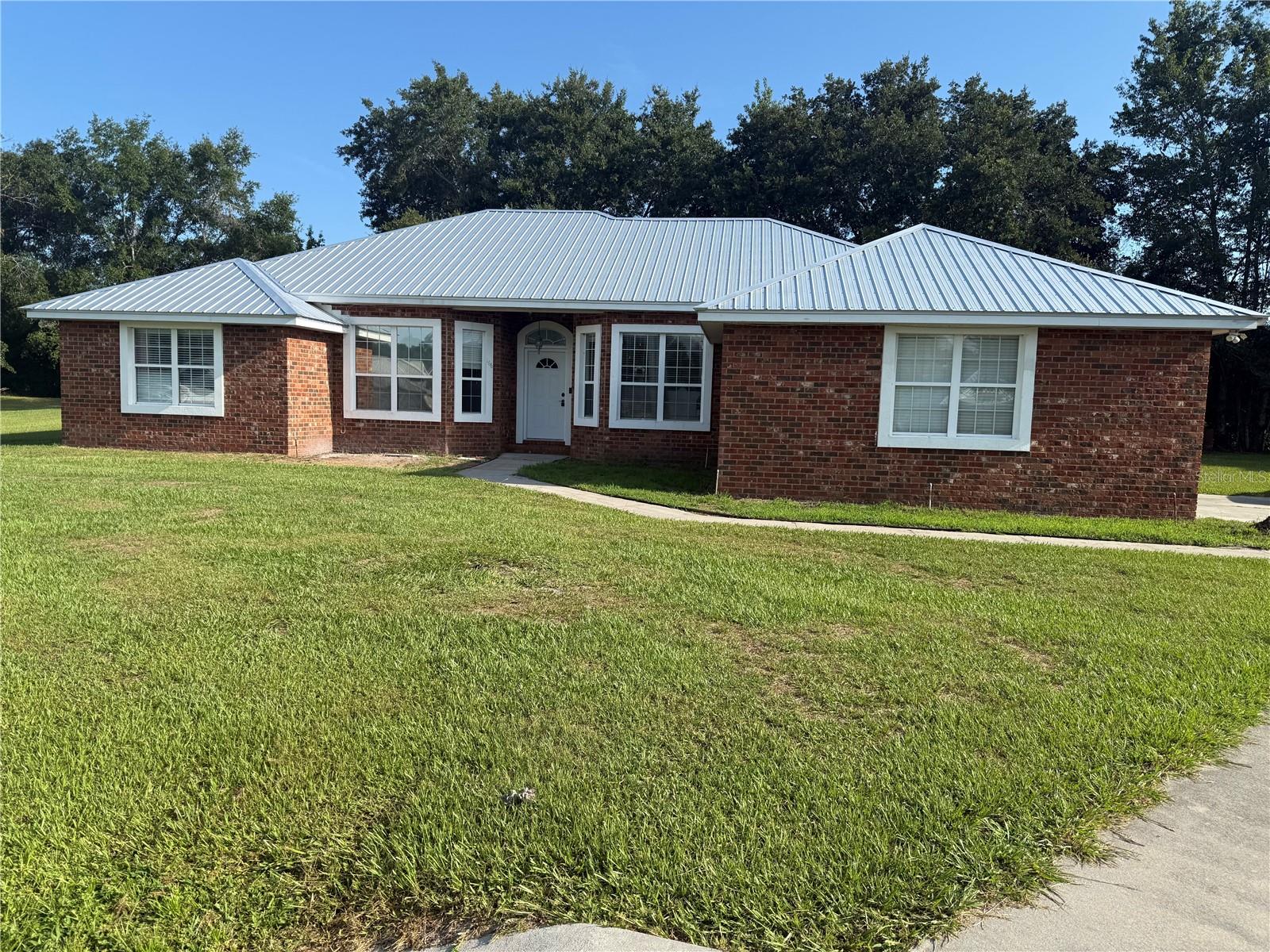 BEAUTIFUL BRICK HOME ON CUL-DE-SAC IN HIGHLY SOUGHT-AFTER NEIGHBORHOOD — NO HOA! Welcome to this well-maintained 4 bedroom, 2 bath home perfectly positioned at the end of a quiet cul-de-sac in one of Lake City's most desirable neighborhoods. Sitting on a spacious half-acre fenced lot, this home offers both privacy and convenience, just minutes from local schools, shopping, restaurants, Lake City Medical Center, and I-75. Step inside to a wide-open living area with a split floor plan that offers ideal flow and functionality. The home features a brand new 2023 metal roof, and HVAC, freshly painted interior, and a two-car garage with a new garage door motor and remotes. You’ll appreciate the professionally installed laminate flooring throughout the living areas, with extra pieces included for the buyer. The kitchen is equipped with stainless steel appliances, and the spacious master suite includes his-and-hers vanities and a large garden tub. Additional the septic and drain field system was updated in 2016 with regular monthly treatments. The backyard is partially fenced and backs up to a wooded area and peaceful retention pond, providing the perfect setting for outdoor enjoyment. This beautiful brick home in a no-HOA neighborhood is move-in ready and offers everything you’ve been looking for. Don’t miss your chance—schedule your private showing today!
