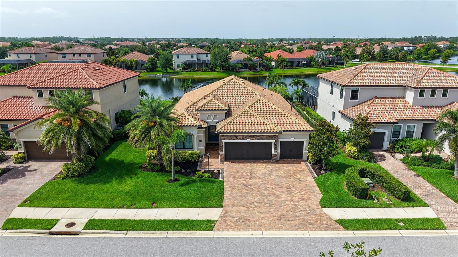 Looking for a truly unique home situated on a tranquil pond in the heart of Lakewood Ranch with more custom touches than you can shake a stick at? Then look no further! This one-of-a-kind Princeton model features everything from an oversized lanai boasting a 37-foot panoramic screen, built-in Breeo fire pit, 9-foot-long paver-constructed bench, remote controlled LED lighting, and even a custom putting green, to a gorgeous outdoor kitchen with stone masonry & tongue-in-groove ceiling -- and that’s just the backyard! The inside of the home is every bit as impressive as the outside, featuring 10-foot ceilings, 8-foot doors, and crown molding & 5 ¼” baseboard throughout the entire home. All of the windows are fully cased in wood trim, and there are custom plantation shutters adorning the entire home. The sliding glass doors leading to the backyard oasis even have their own remote-control roll-down fabric shades for convenience and privacy. You will not find one bit of wire shelving in any of the bedrooms or in the kitchen pantry, as those areas have all been upfitted with custom wood shelving. Is the master bedroom spacious? Yes. Are the bathrooms beautifully appointed with wood cabinets, stone counters, and upgraded lighting & plumbing fixtures? You bet. And do the living areas have an open flow that we have come to expect from a high-end Florida home? Absolutely. But the showstopper in this home is undoubtedly the amazing kitchen. The 6.5’ x 7’ island can handle any family gathering that you throw at it. And, amazingly, it features one single, gorgeous slab of quartzite. The built-in oven/microwave combo, along with the range, range hood, and dishwasher are all KitchenAid, and the refrigerator is Thermador. All of the cabinets are full wood construction with dovetail joinery and soft-close drawers & doors. Above the range is a fully functional pot-filler for the chef in the family. Simply put, this home has it all. So don’t hesitate – book your showing today. This one won’t last long!
